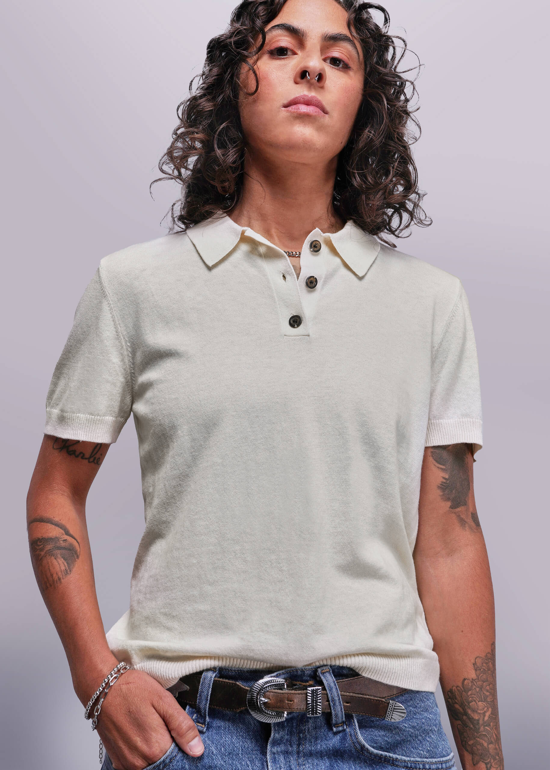 S=Person wearing a light-colored polo shirt and jeans against a plain background