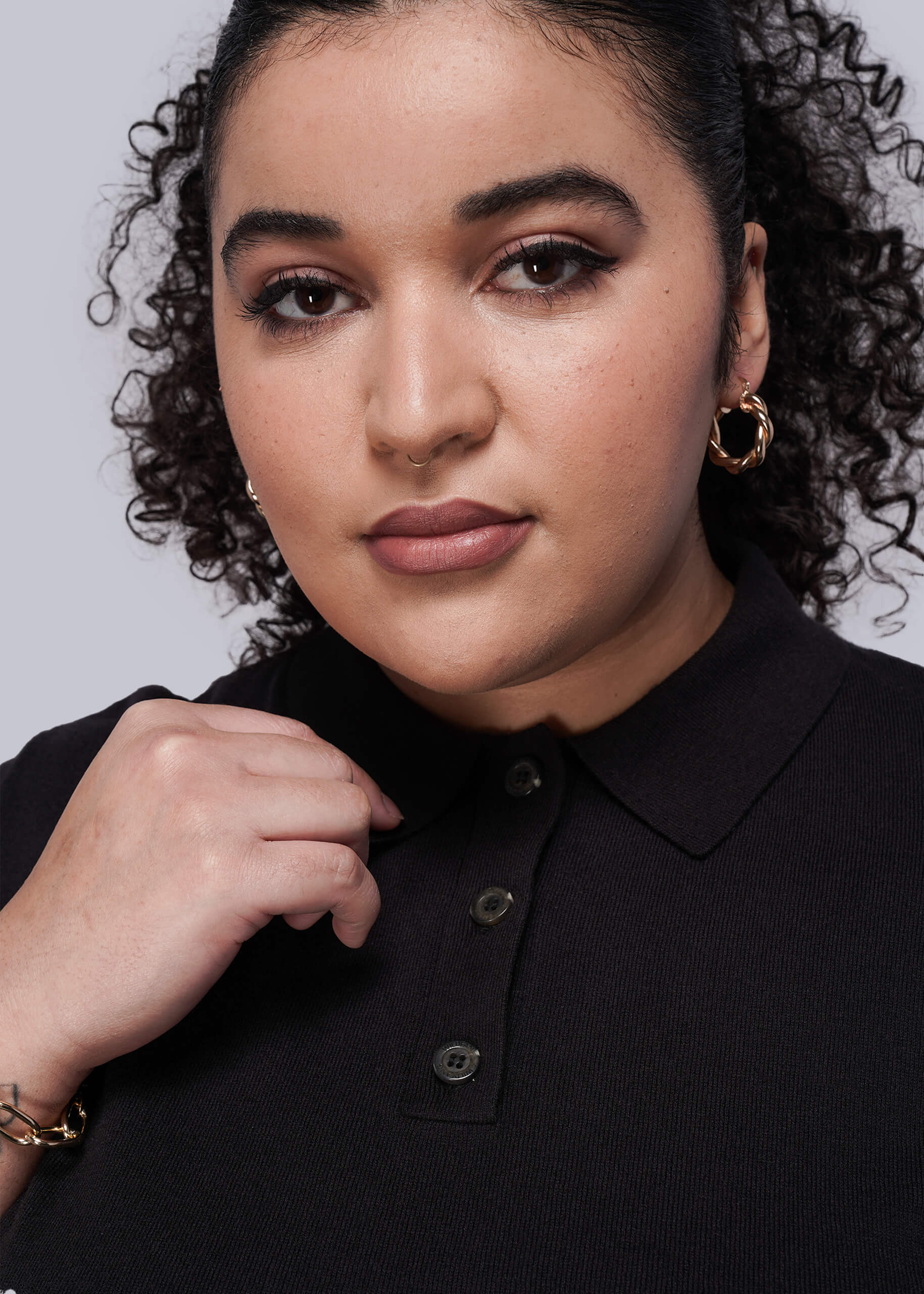 1X=Woman wearing a black shirt with a plain background