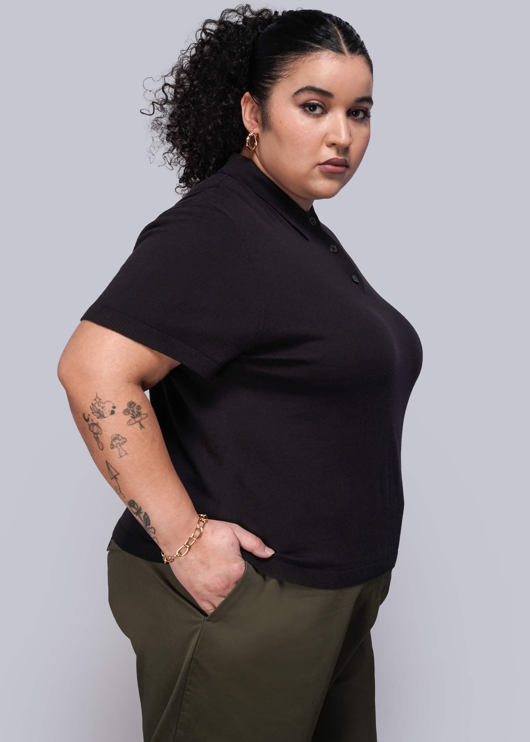 1X=Person wearing a black polo shirt and green pants against a plain background