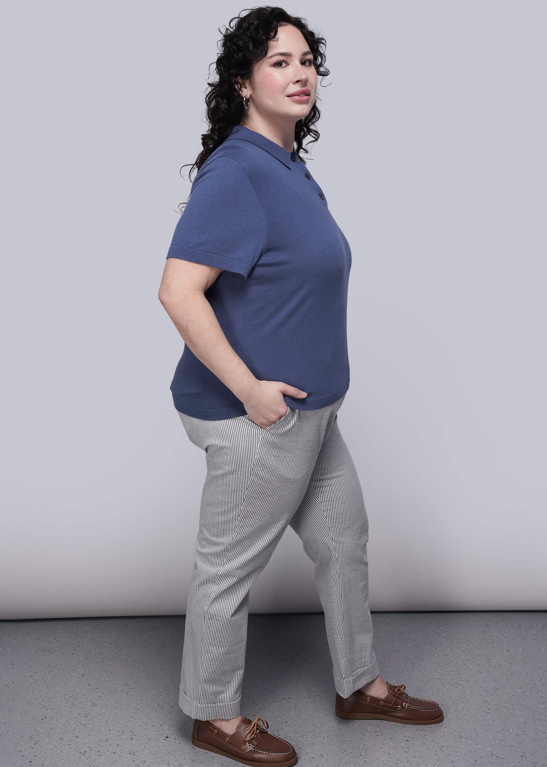 1X=Person wearing a blue shirt and striped pants against a plain background