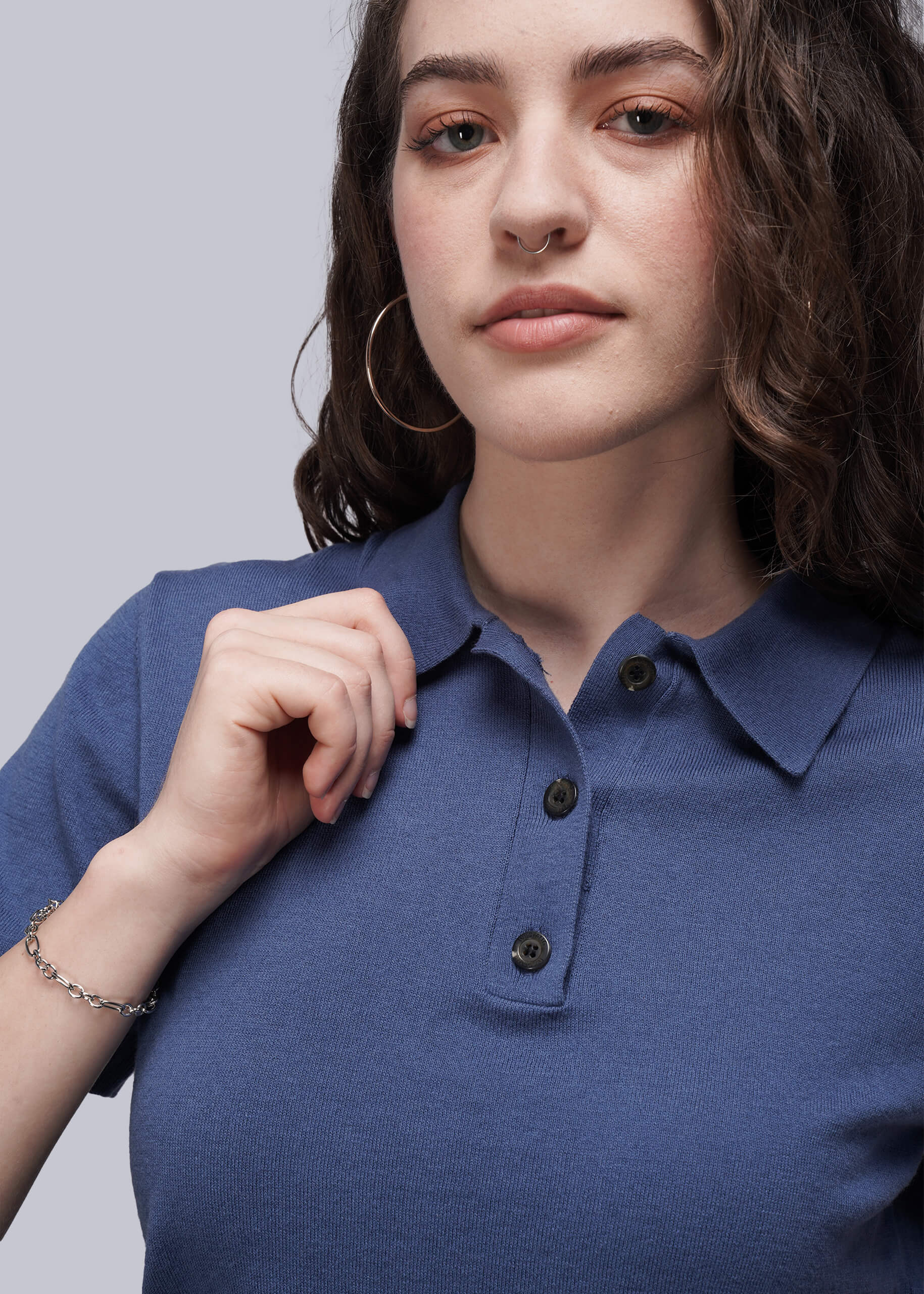 Woman wearing a blue polo shirt against a plain background