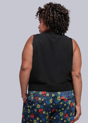 1X=Person wearing a black sleeveless top and colorful floral pants on a plain background