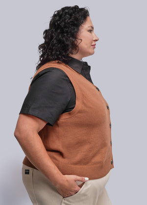 1X=Person wearing a brown vest over a black shirt on a plain background