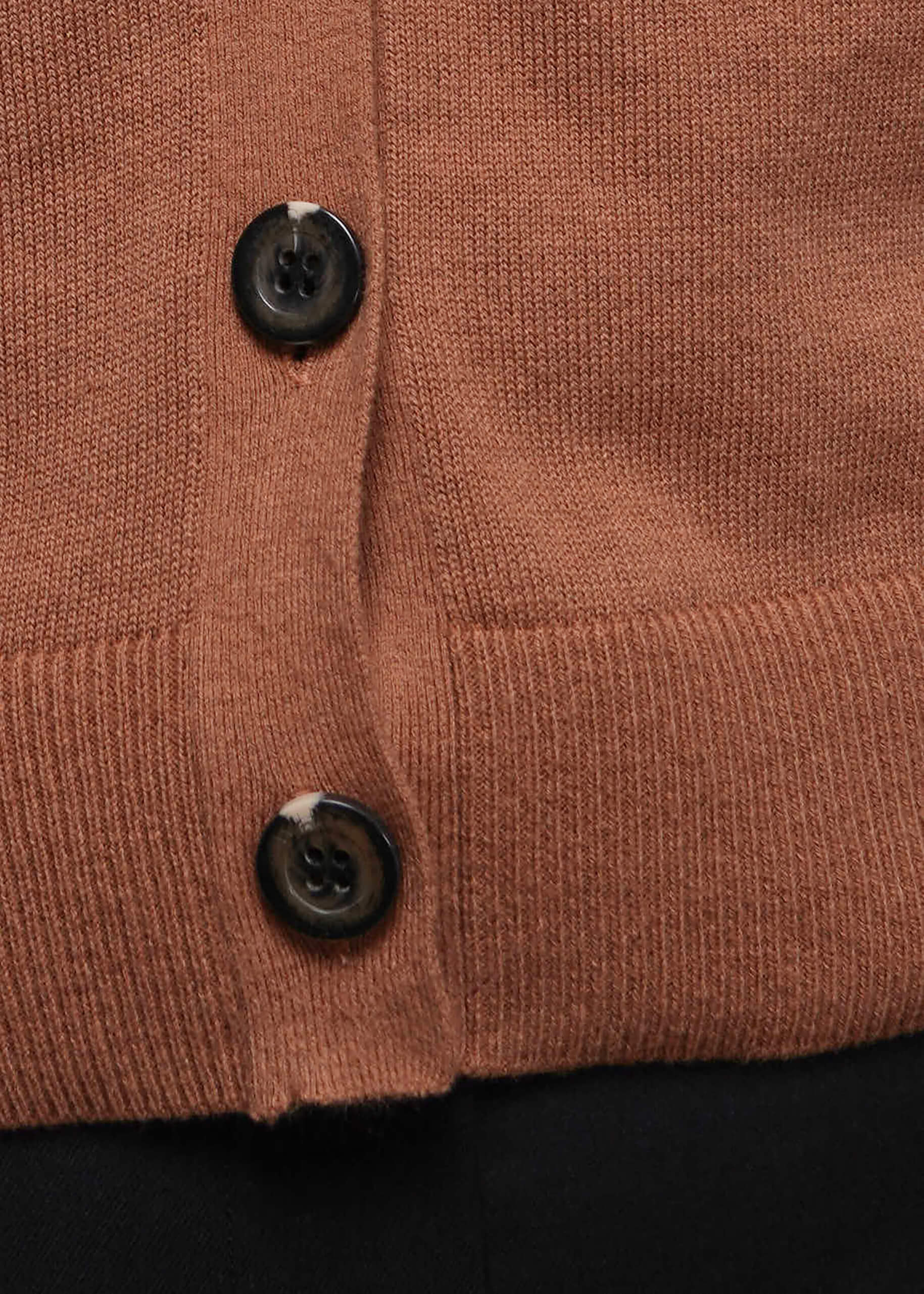 S=Close-up of a brown knitted vest with two buttons on a black background