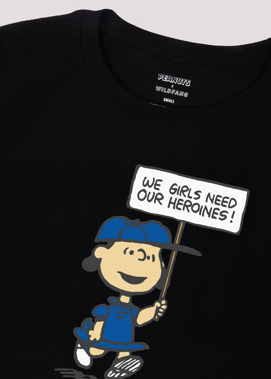Close up of The Peanuts x Wildfang Heroines Graphic Tee, which is a black tee that features a graphic of Lucy with a sign that says 