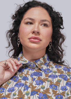 1X=Person wearing a floral patterned shirt against a plain background