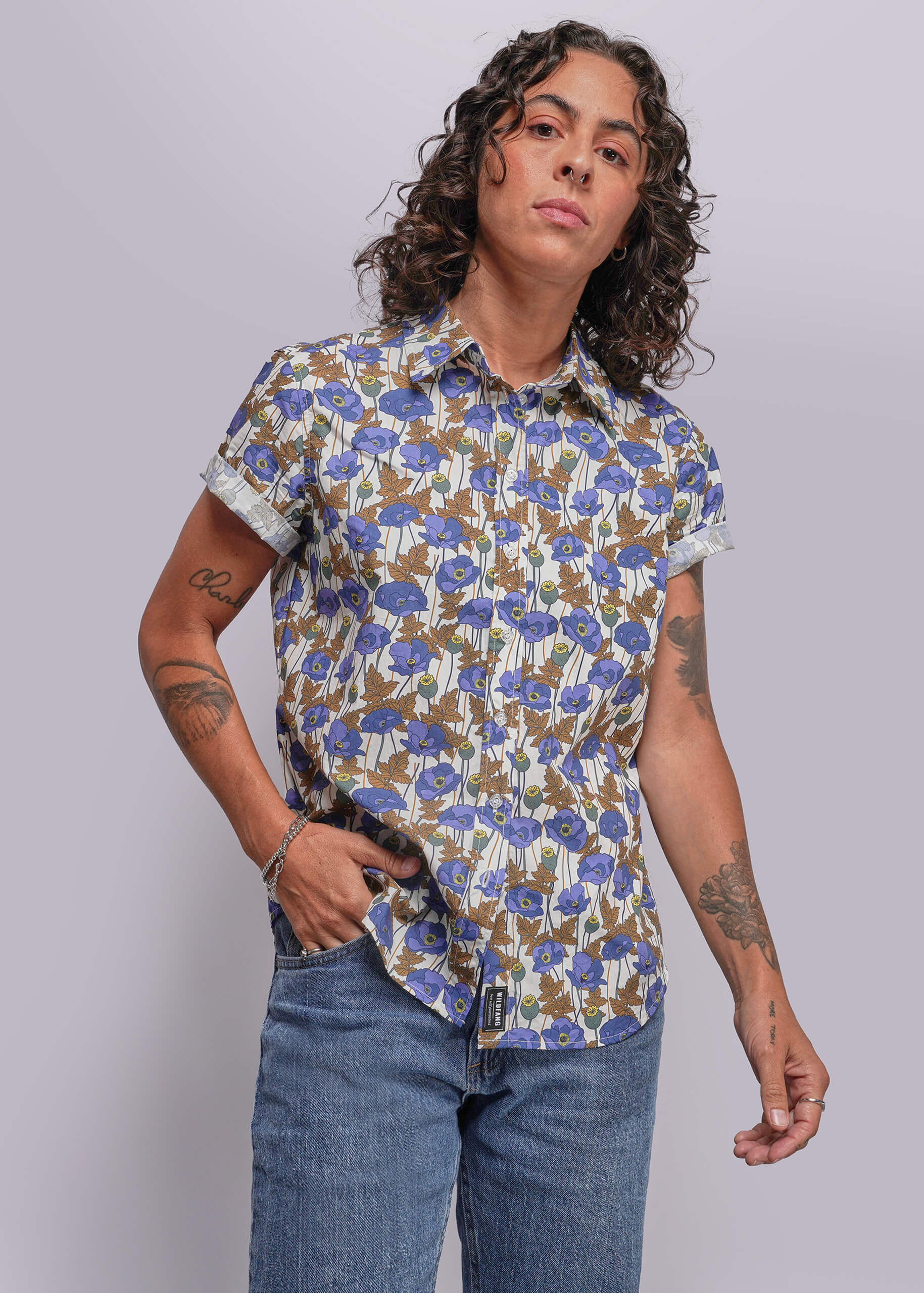 S=Person wearing a floral short-sleeve shirt and jeans against a plain background