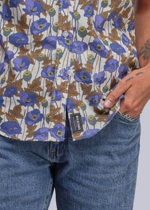 S=Close-up of a floral-patterned shirt with a visible brand label, worn by a person.