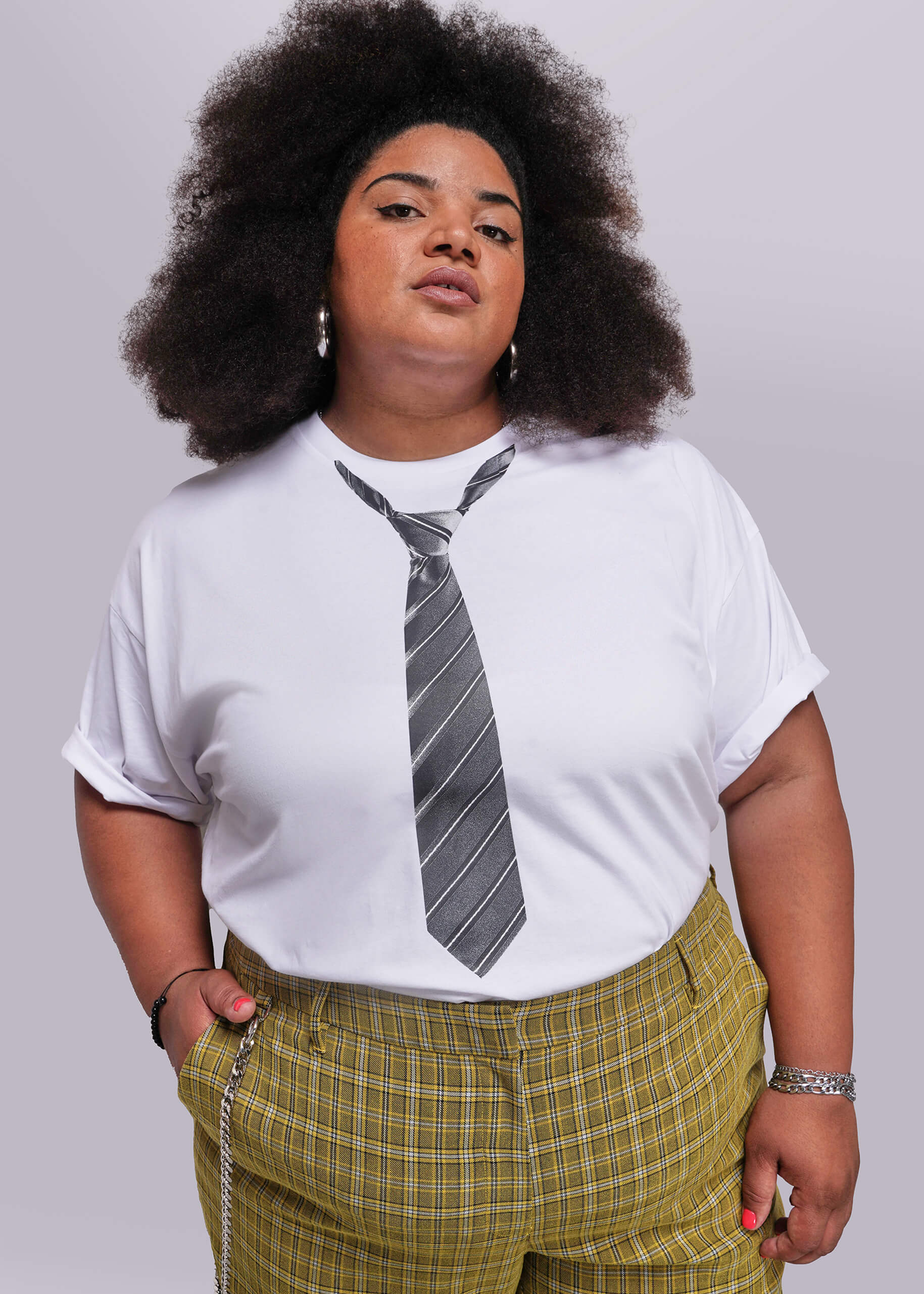 1X=Person wearing a white t-shirt with a tie design and yellow plaid pants on a plain background