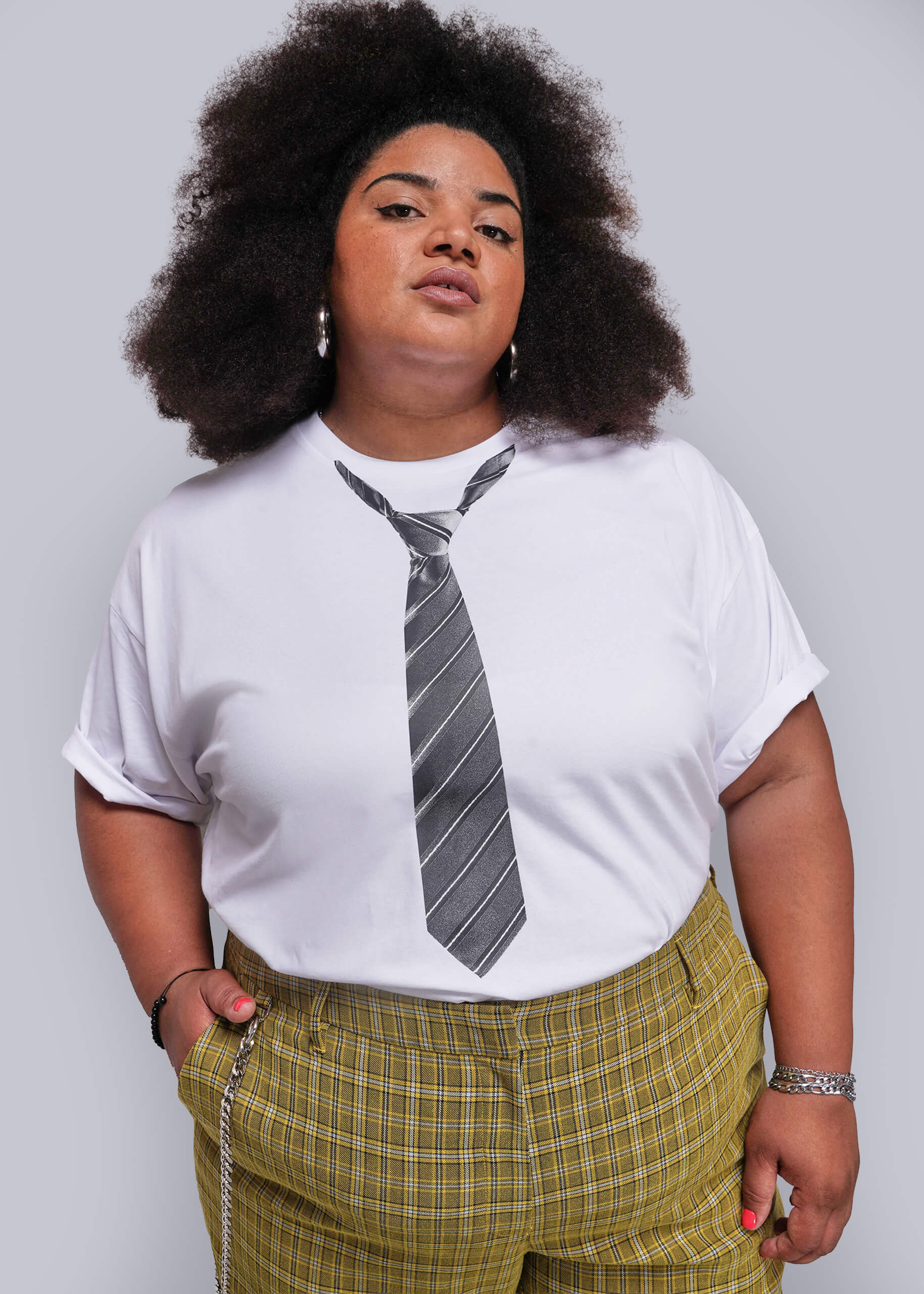 1X=Person wearing a white t-shirt with a tie design and yellow plaid pants on a plain background