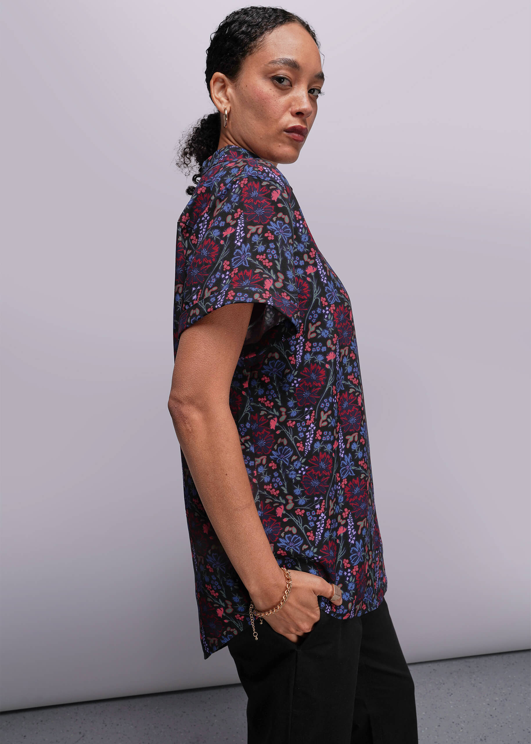 S=Person wearing a patterned shirt from side against a plain background