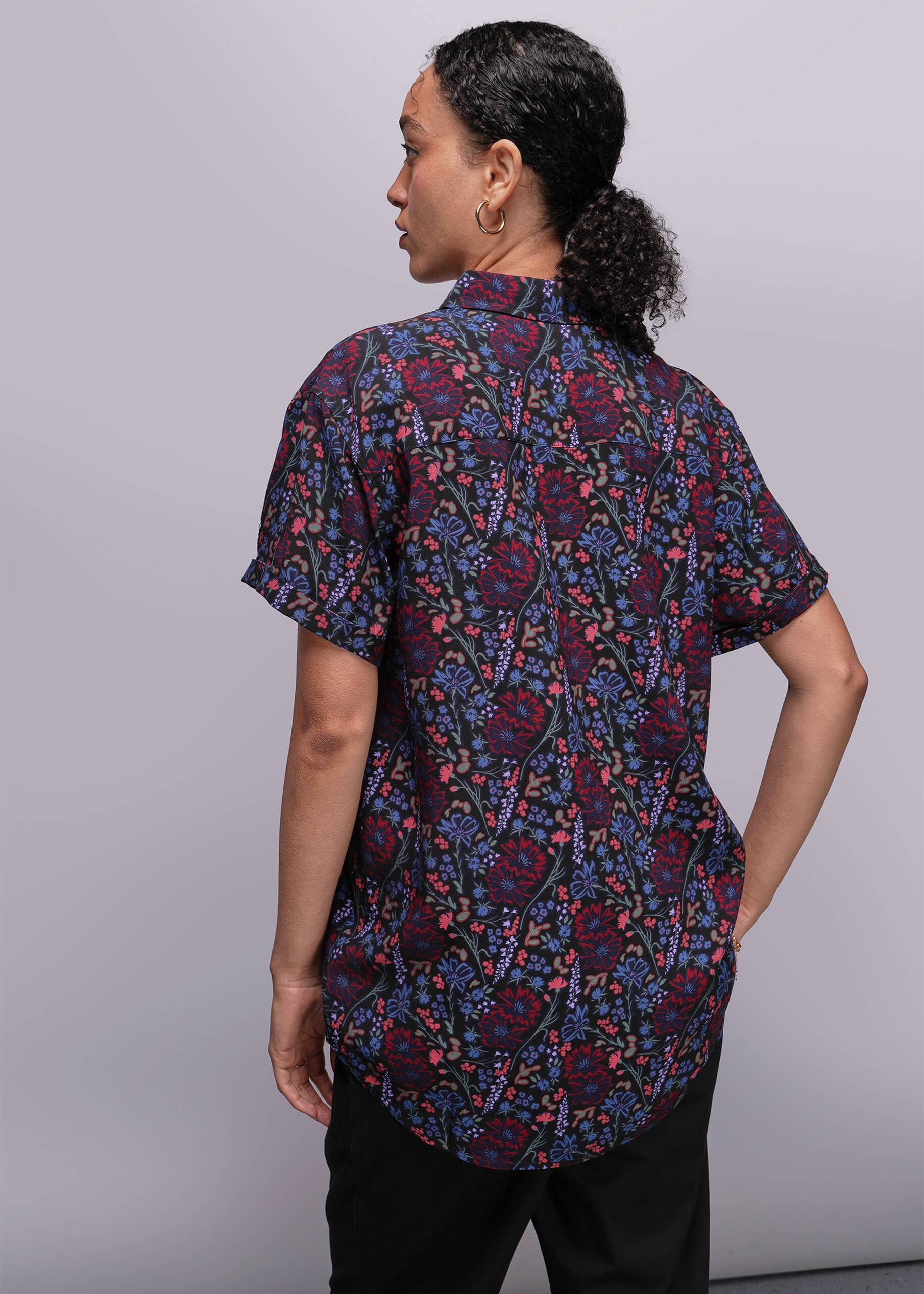 S=Back of person wearing a patterned shirt with a plain background