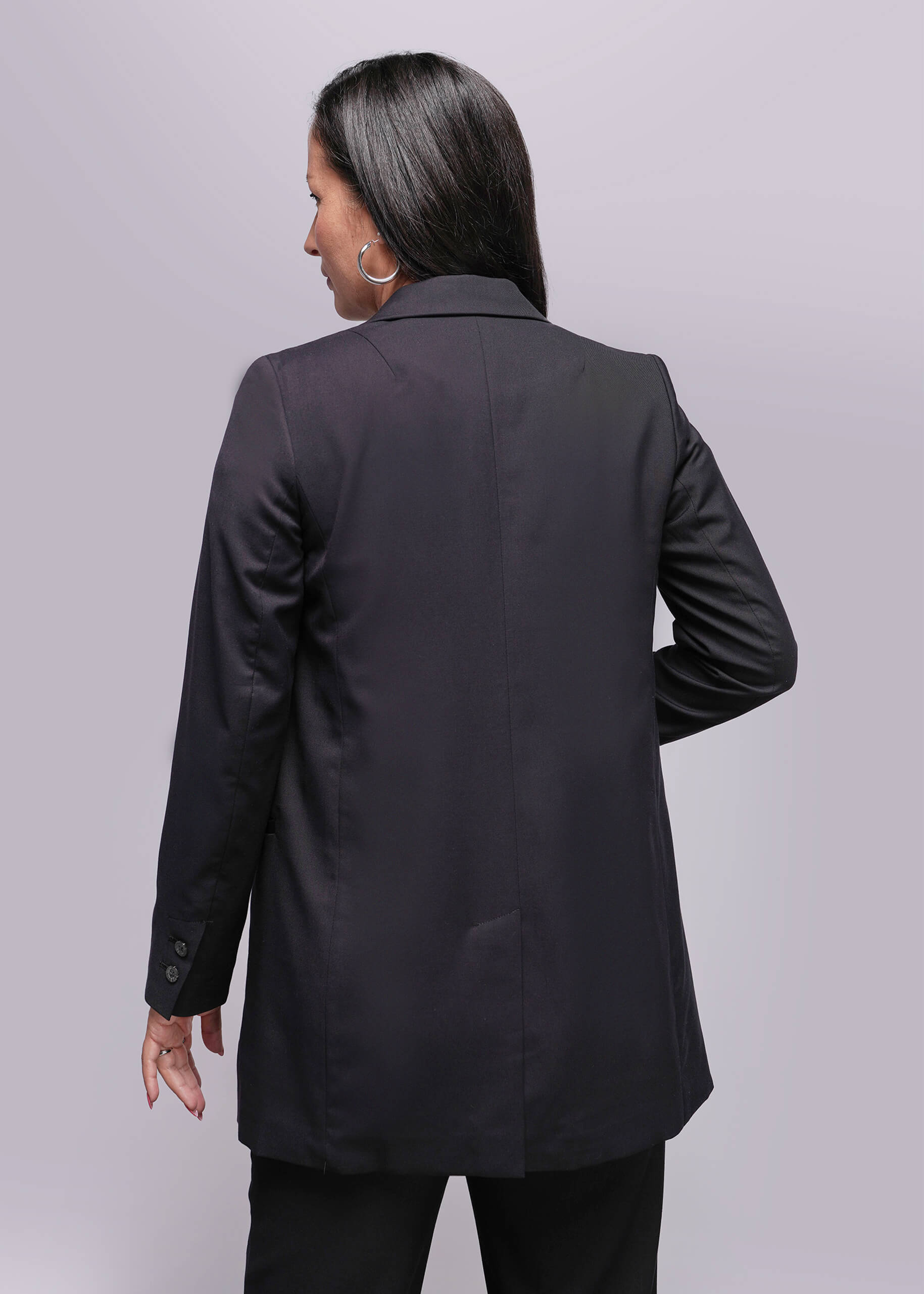 S=Person wearing a black blazer from behind on a light gray background
