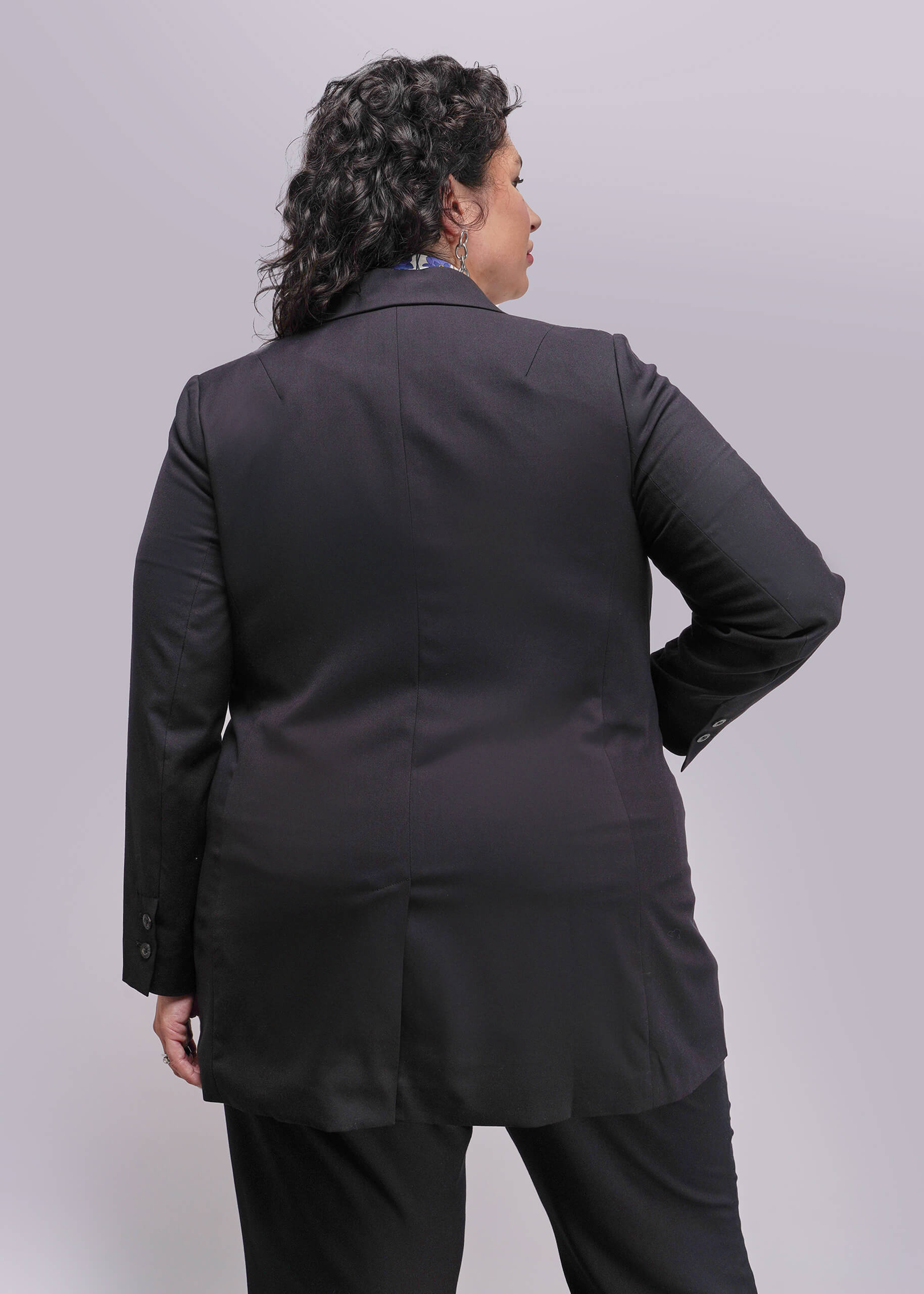 1X=Person wearing a black suit against a plain background