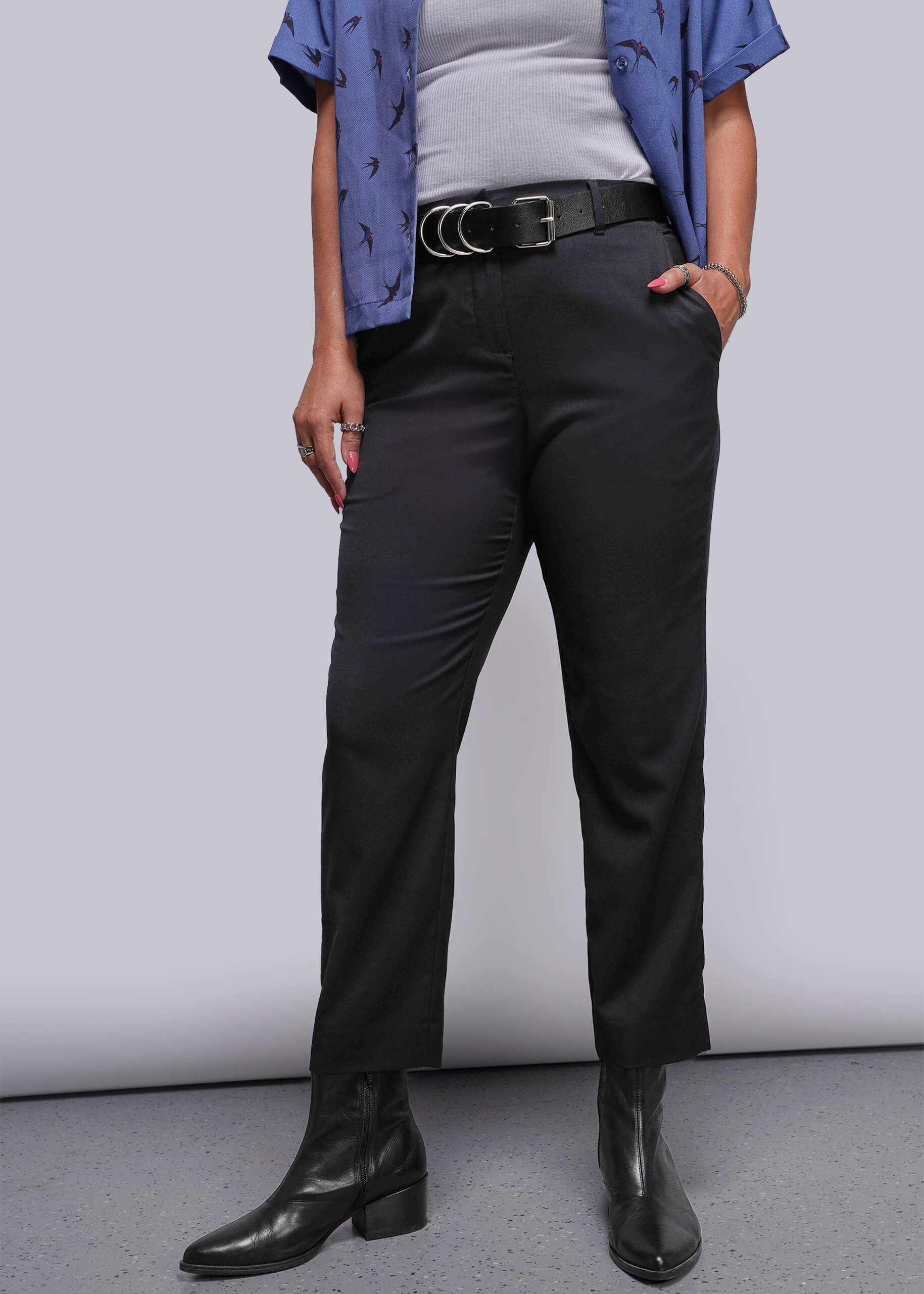 Person wearing black pants with a blue shirt and white top against a plain background