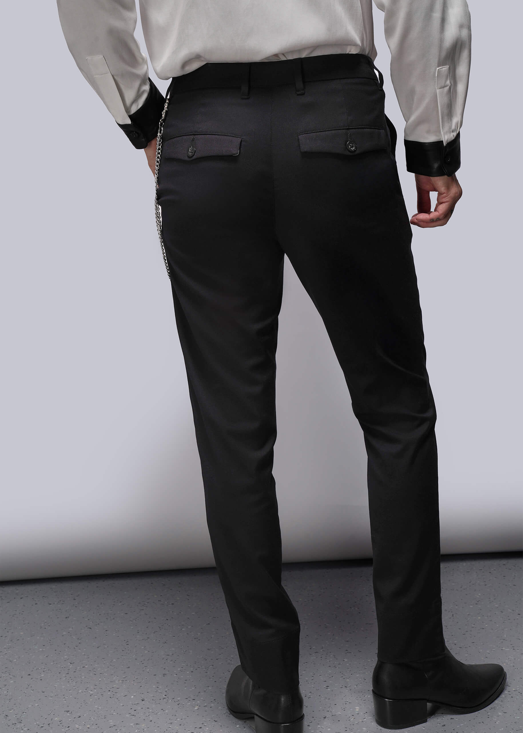 Back view of Person wearing black pants and a light-colored shirt on a plain background