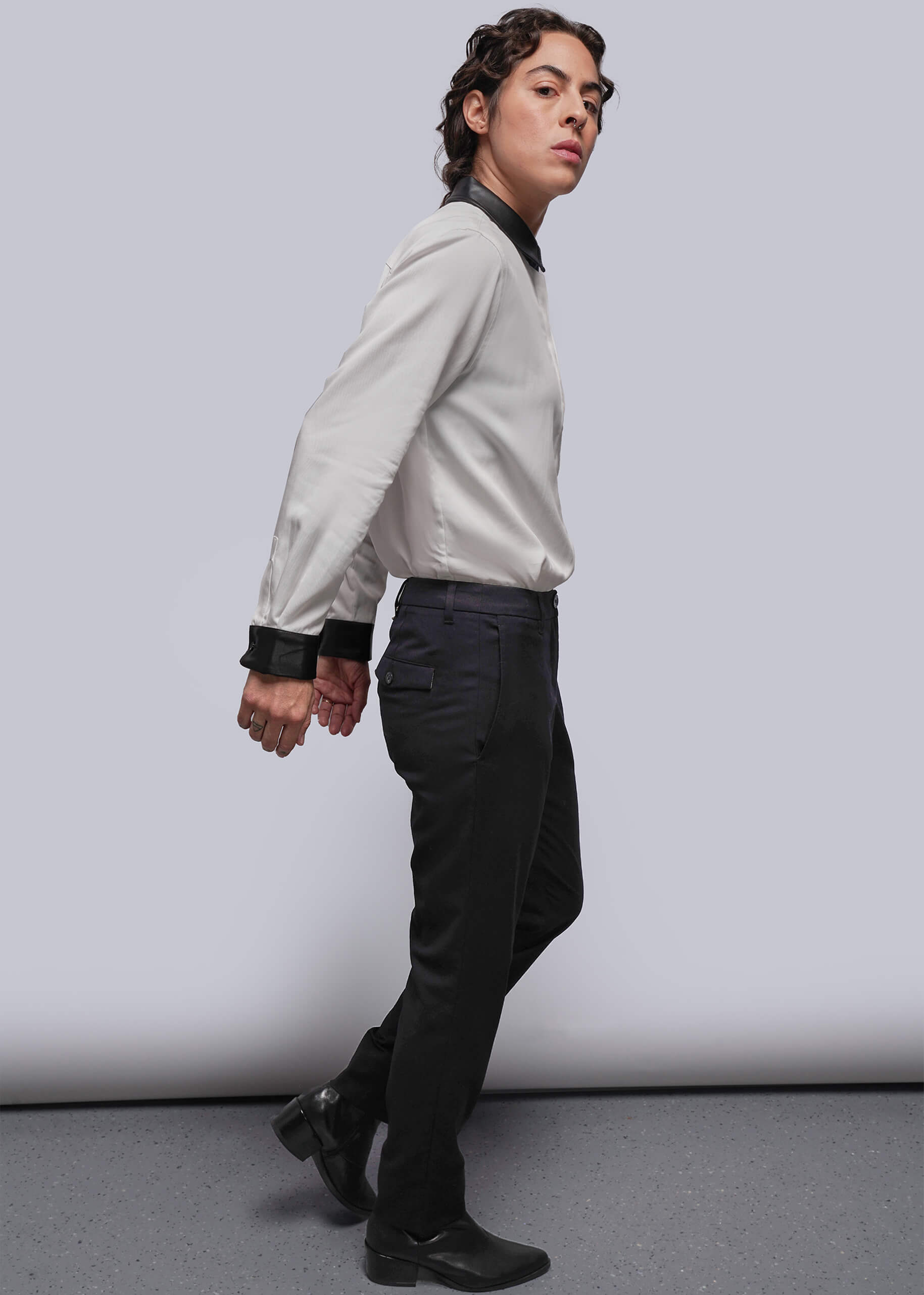 S=Person wearing a light shirt and dark pants against a plain background