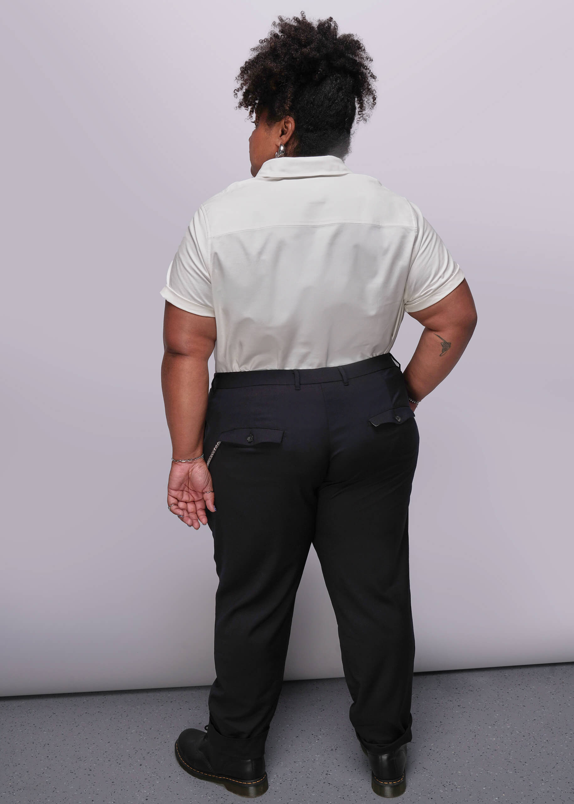 1X=Person wearing a white shirt and black pants against a plain background