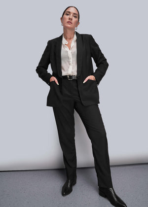 S=Person wearing a black suit with a white shirt on a gray background