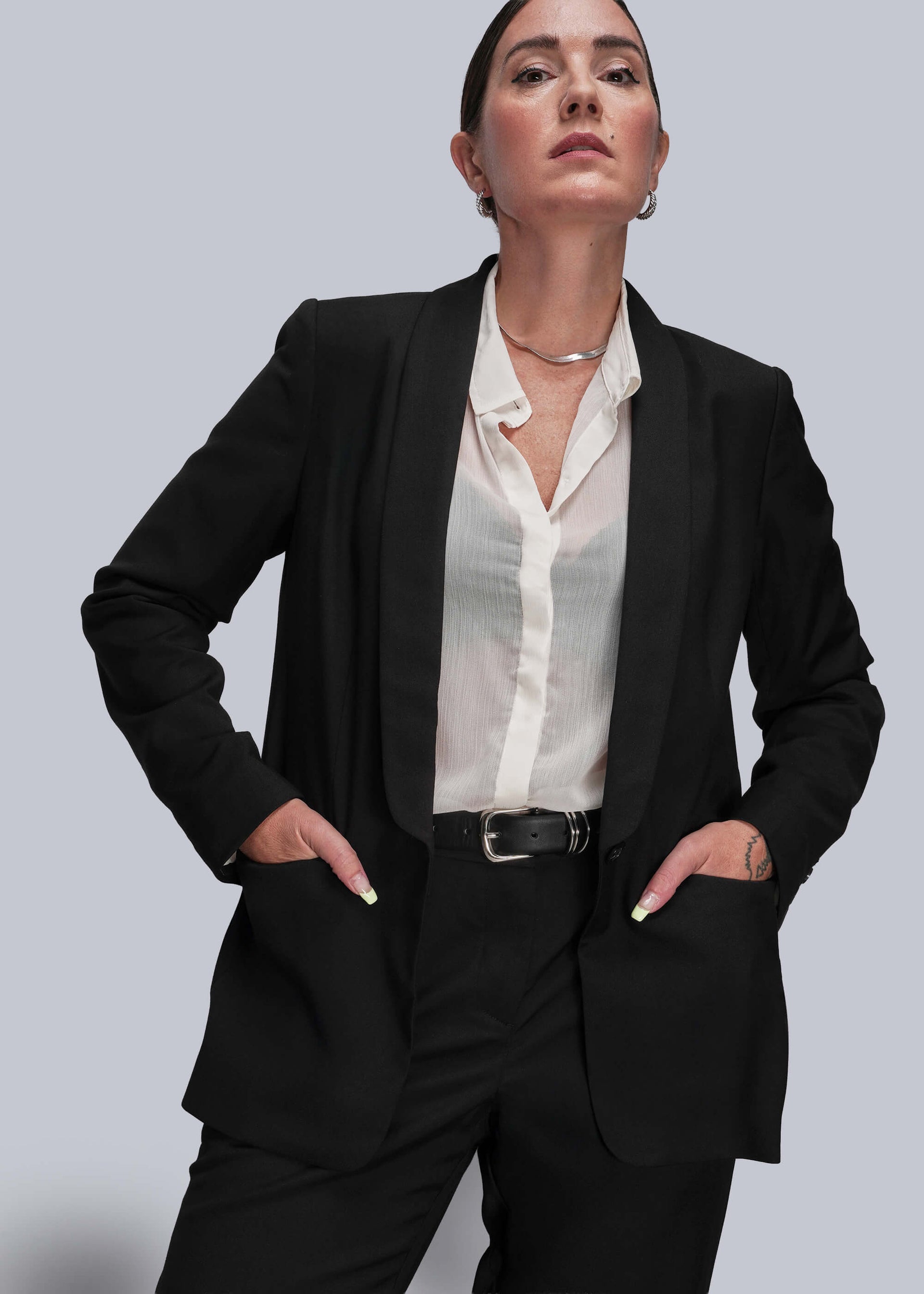 S=Person wearing a black suit with a white shirt on a light gray background