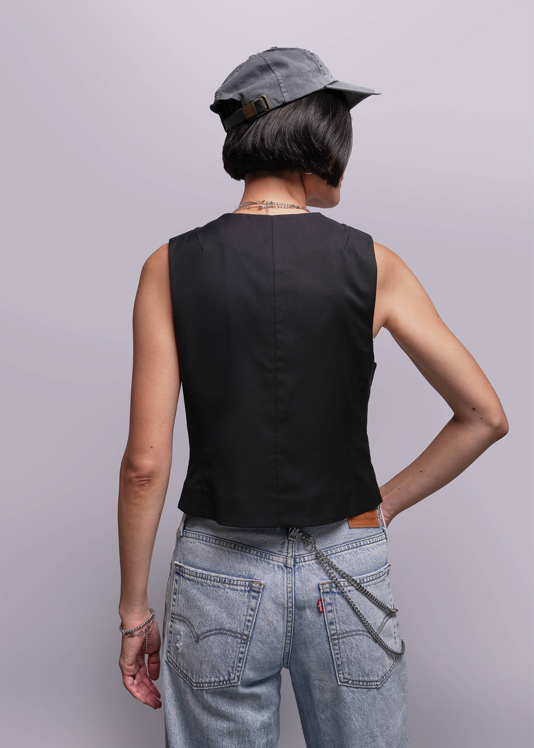S=Person wearing a black sleeveless top and light blue jeans with a gray cap on a plain background