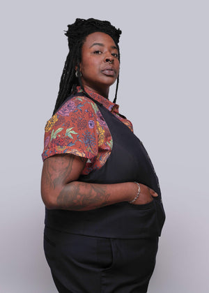 S=Person wearing a black outfit with a colorful floral shirt over the shoulders against a white background