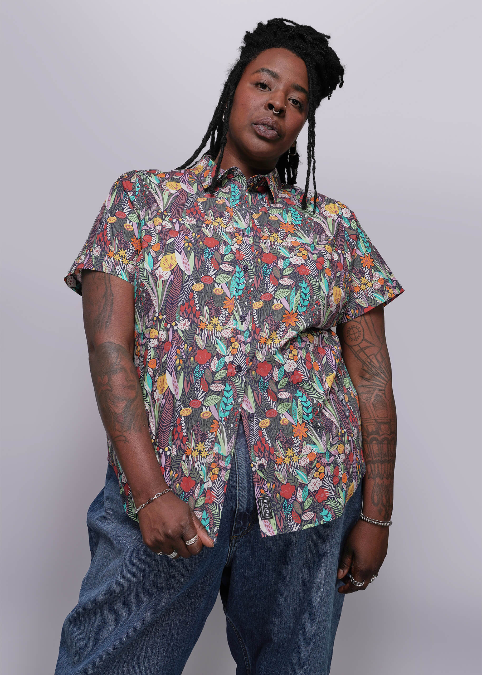 1X=Person wearing a colorful patterned shirt and jeans against a white background