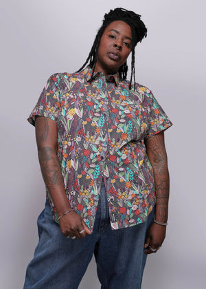 1X=Person wearing a colorful patterned shirt and jeans against a white background