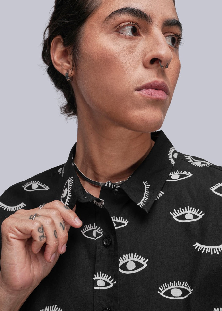 Person wearing a black shirt with white eye pattern against a gray background
