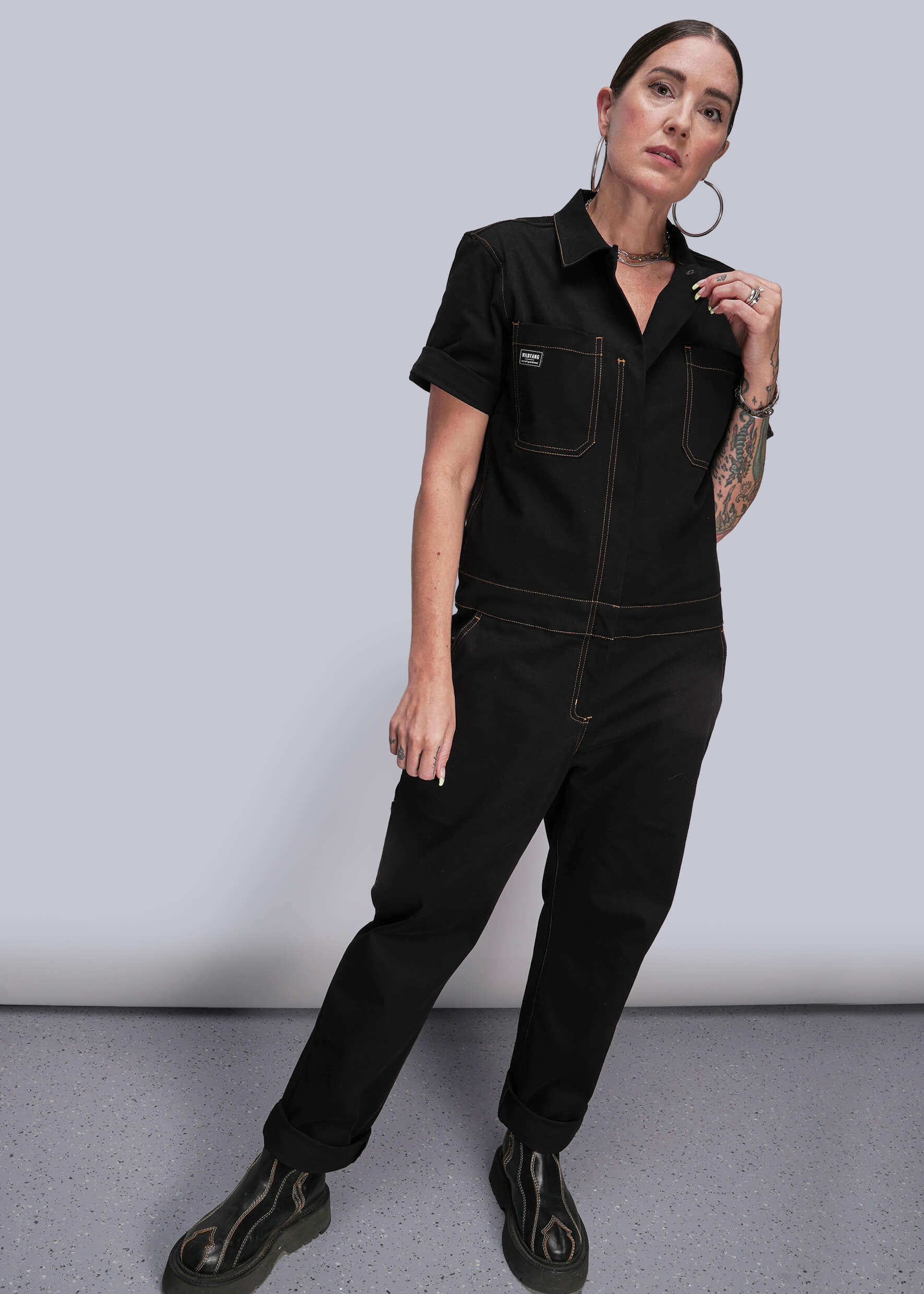 S=Person wearing a black jumpsuit against a plain background