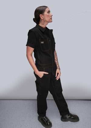 S=Person wearing a black work uniform with a vest and pants on a plain background