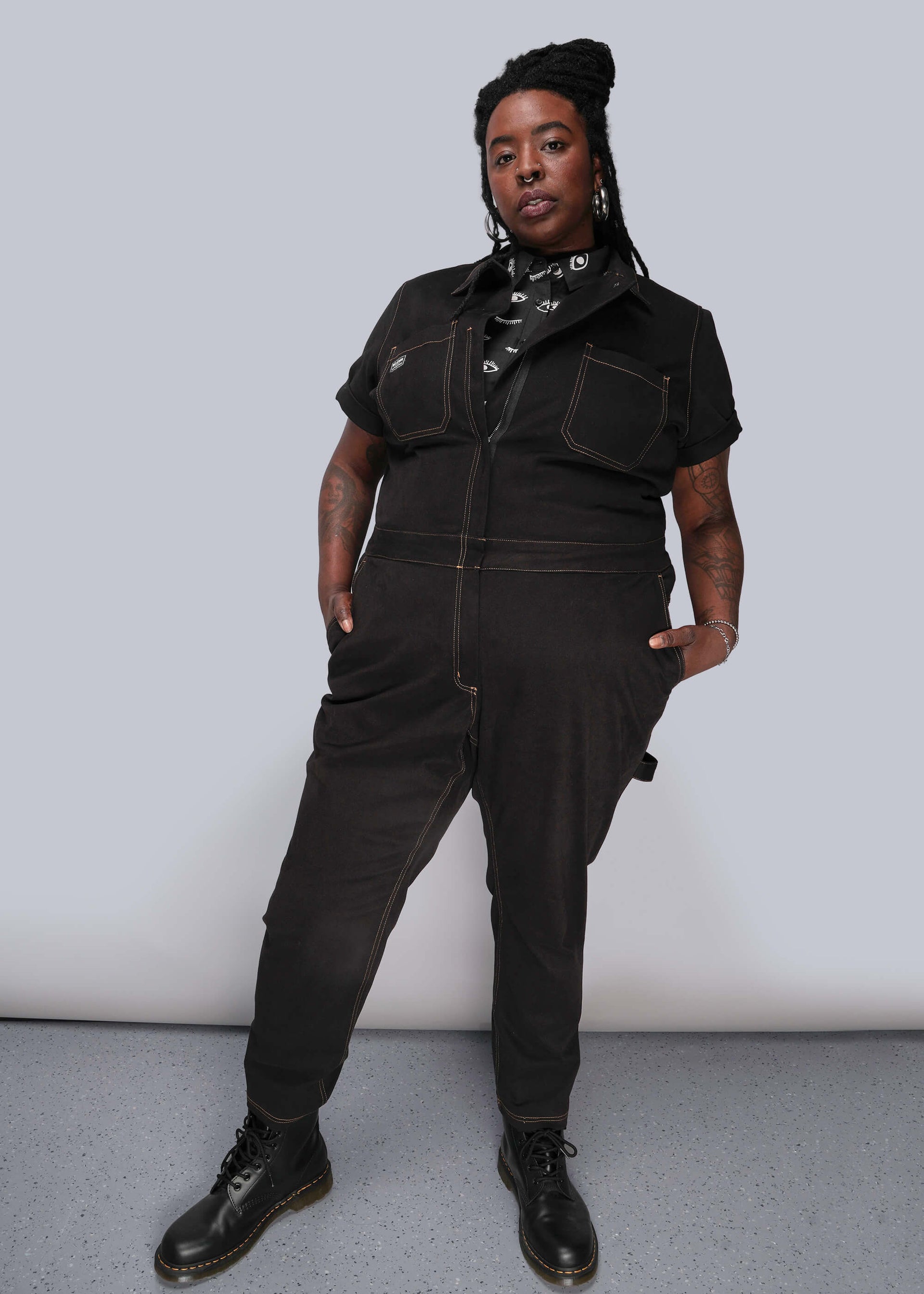 1X=Person wearing a black jumpsuit against a plain background