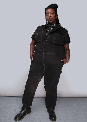 1X=Person wearing a black jumpsuit against a plain background