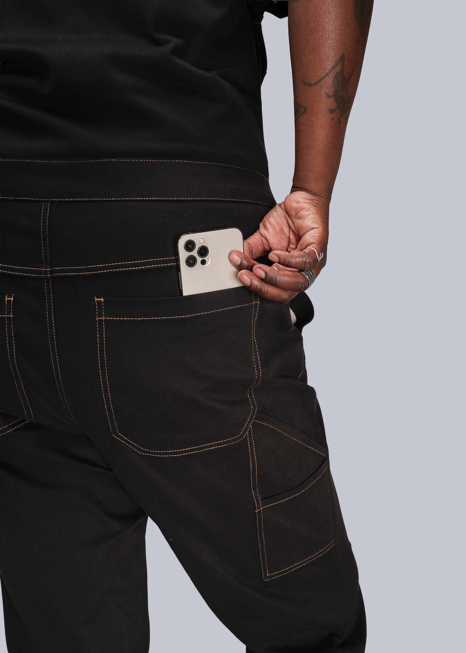 1X=Person placing a phone in back pocket of black jumpsuit