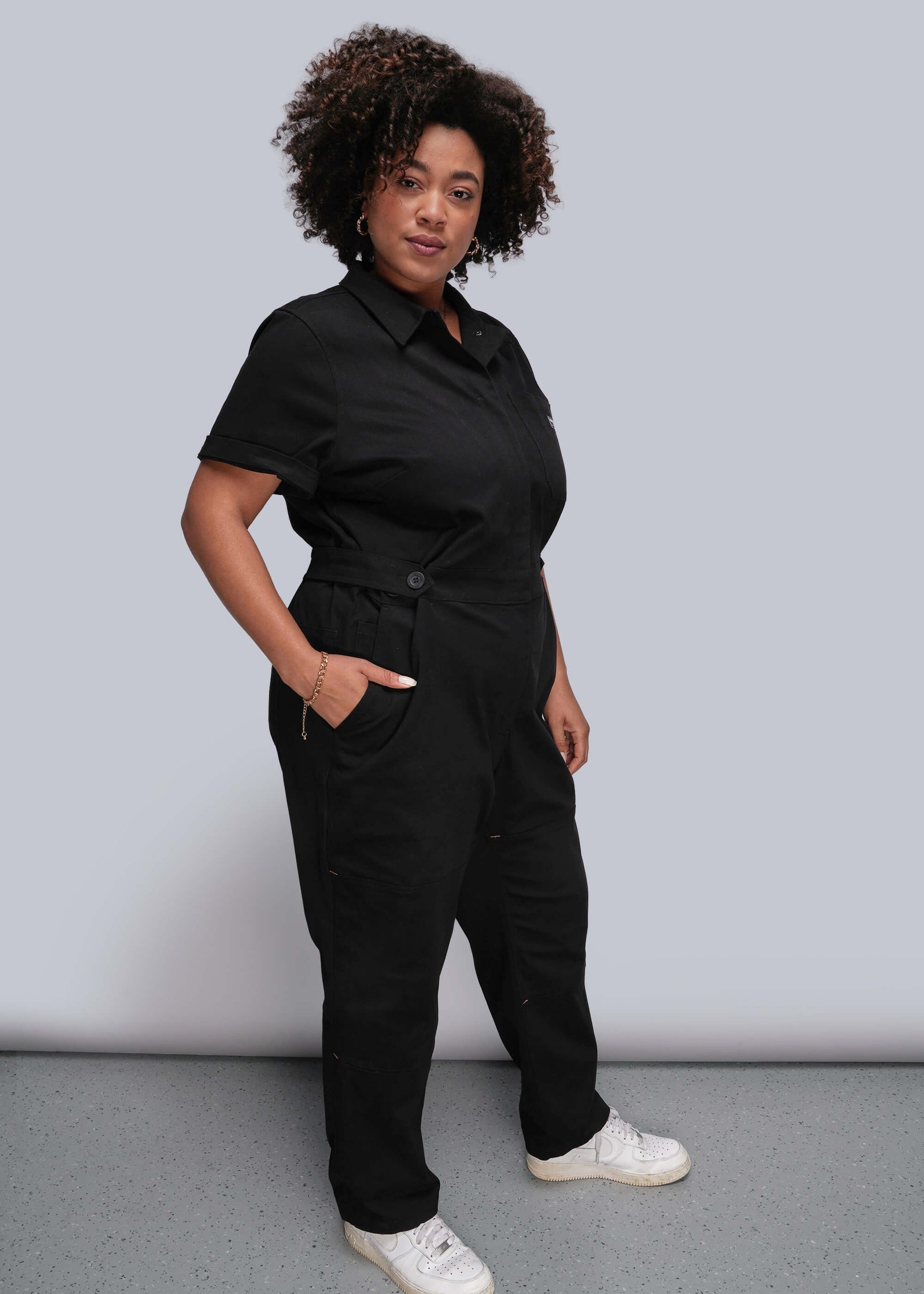 1X=Person wearing a black jumpsuit against a plain background