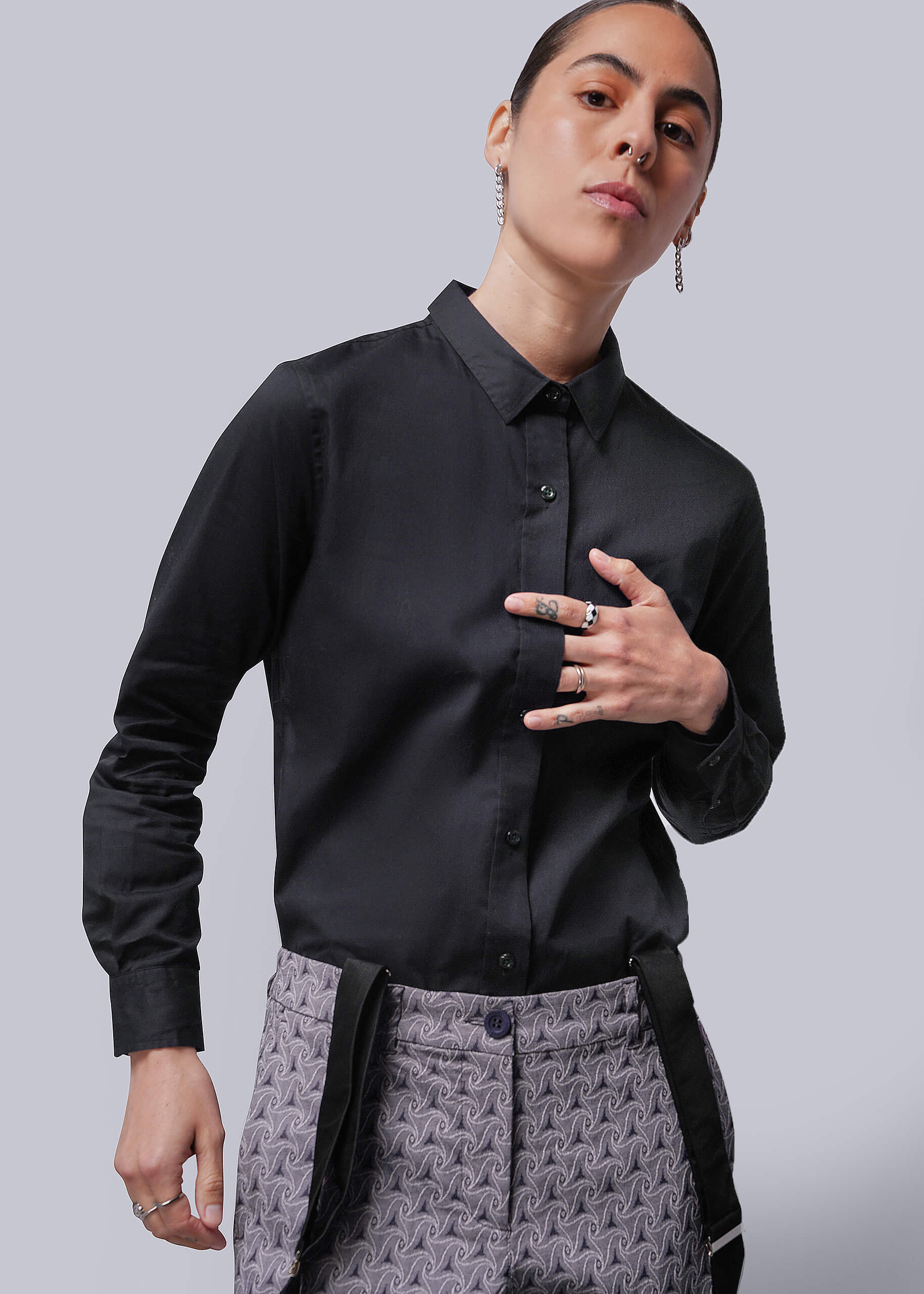 Person wearing a black shirt and patterned pants on a plain background