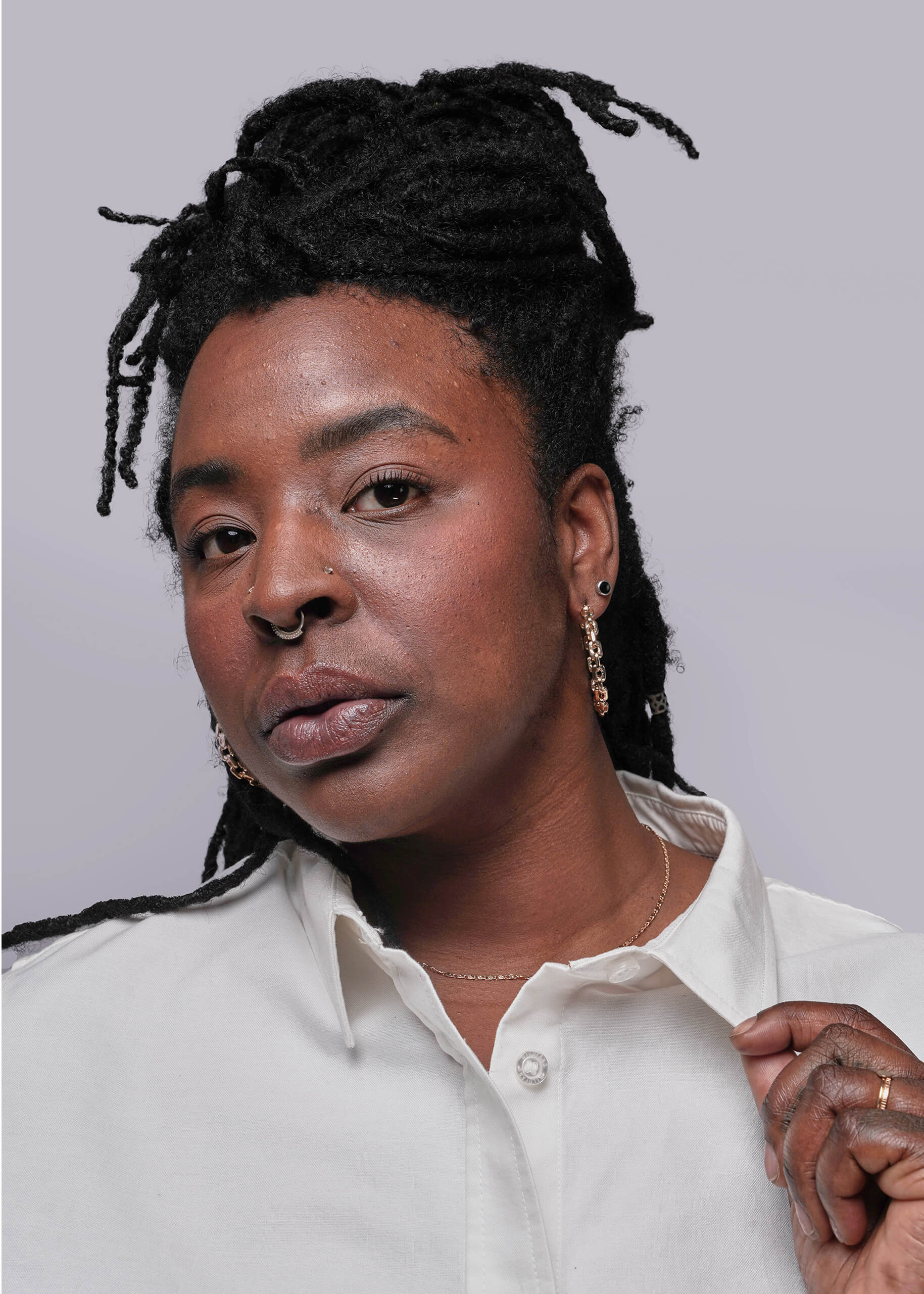 1X=Close up of Person wearing a white shirt against a plain background