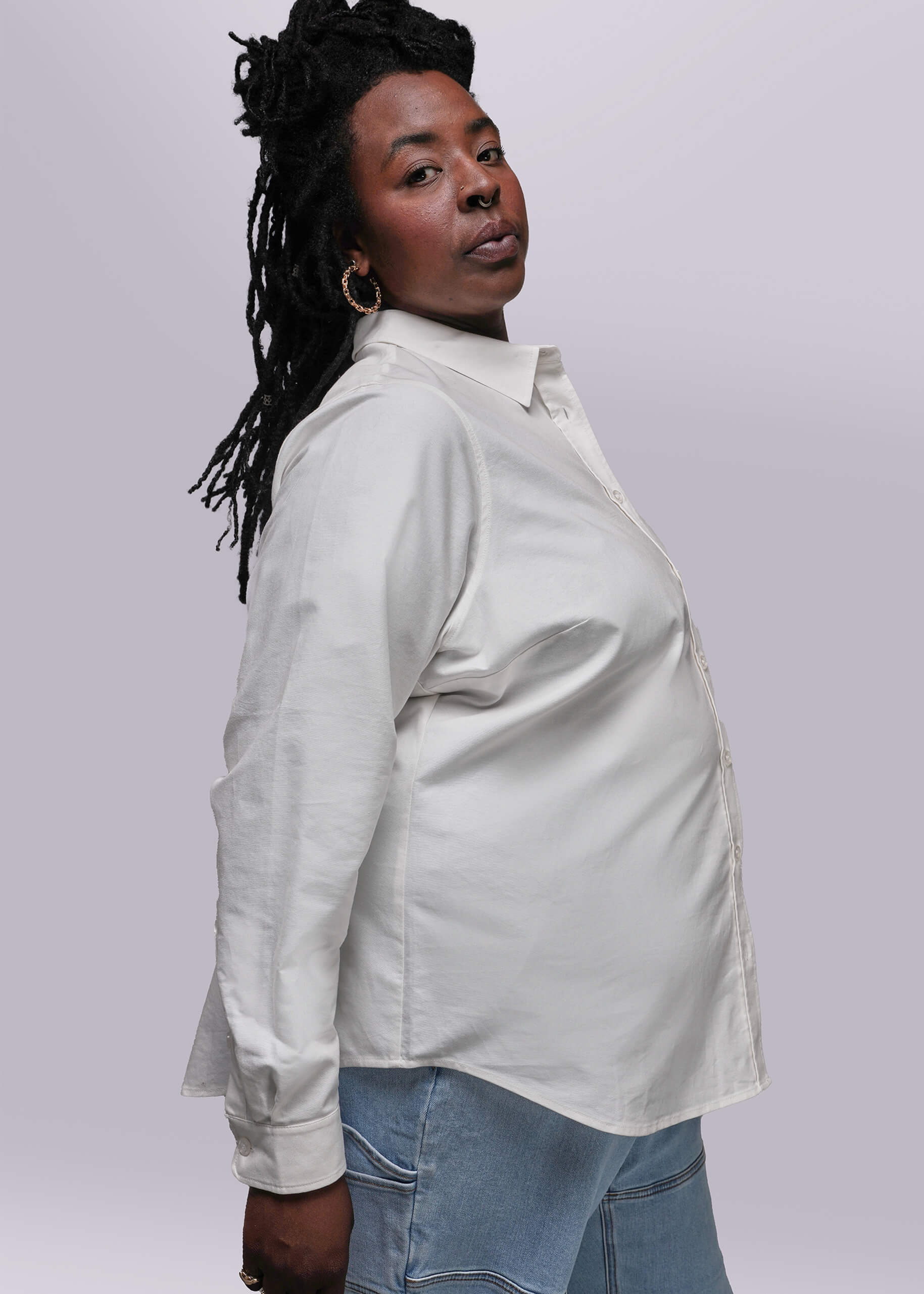 1X=Side view of Person wearing a light-colored shirt and jeans against a plain background