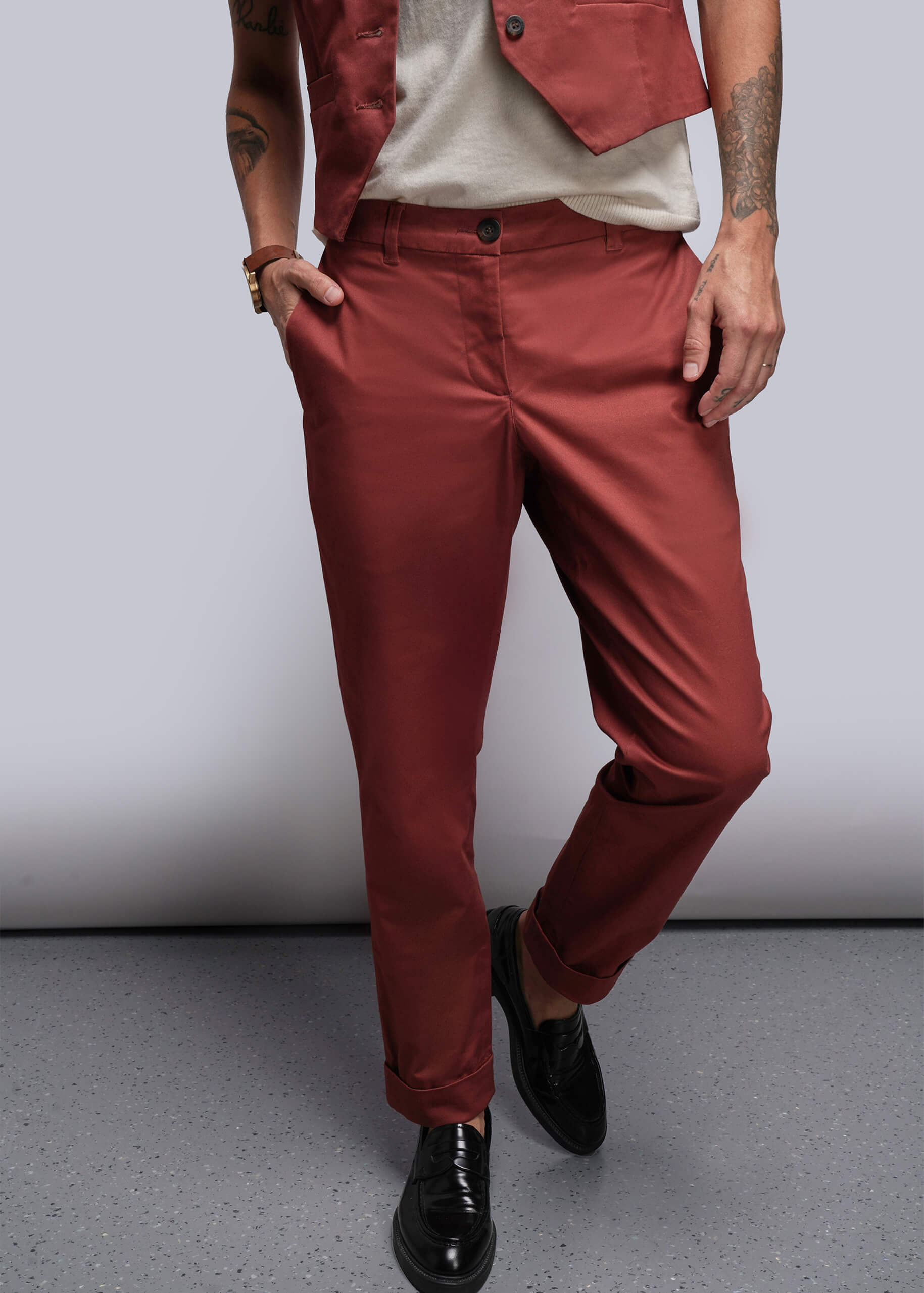 Person wearing cinnamon colored pants and a cinnamon vest against a plain background