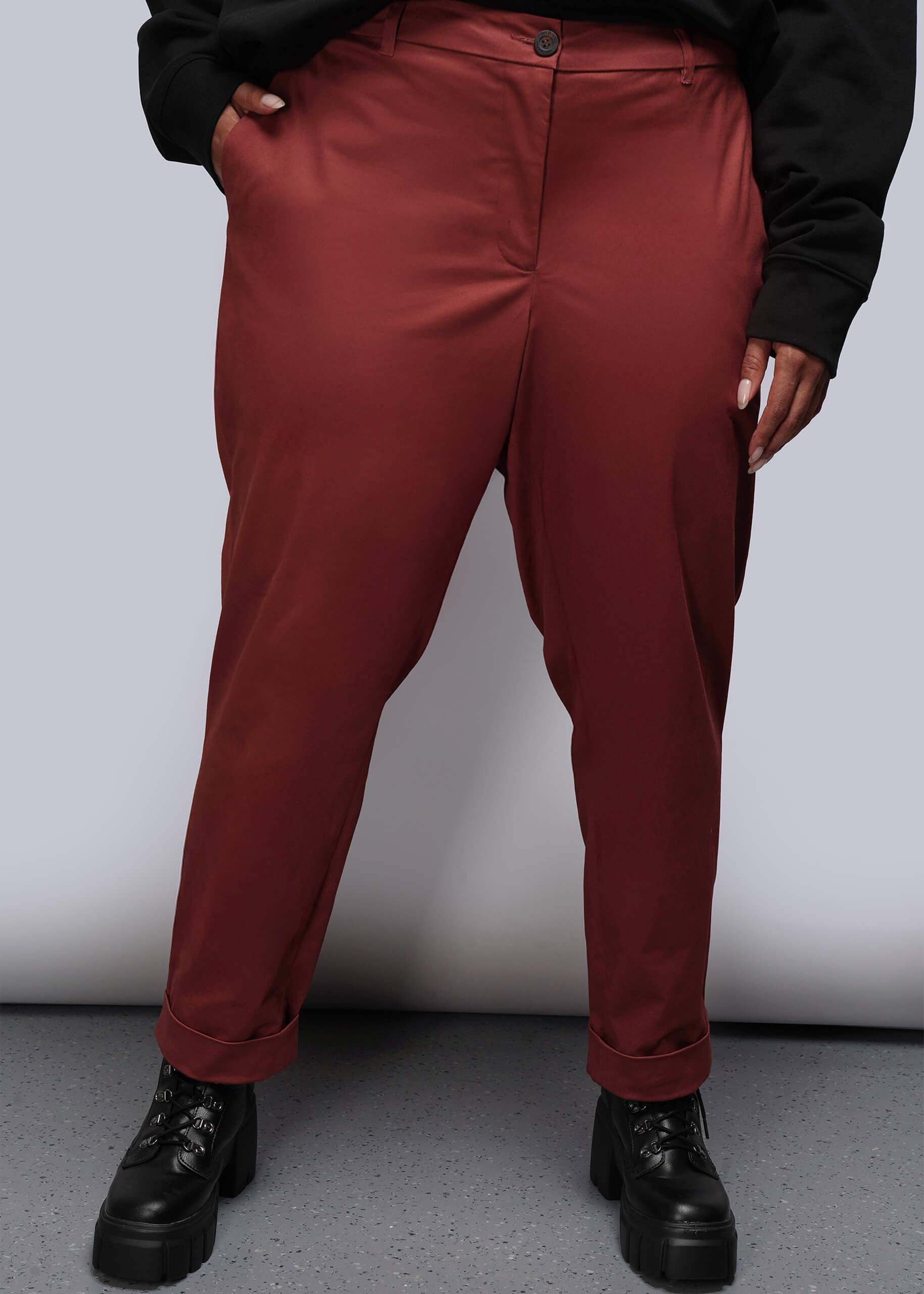 1X=Person wearing red orange pants and black shoes on a plain background