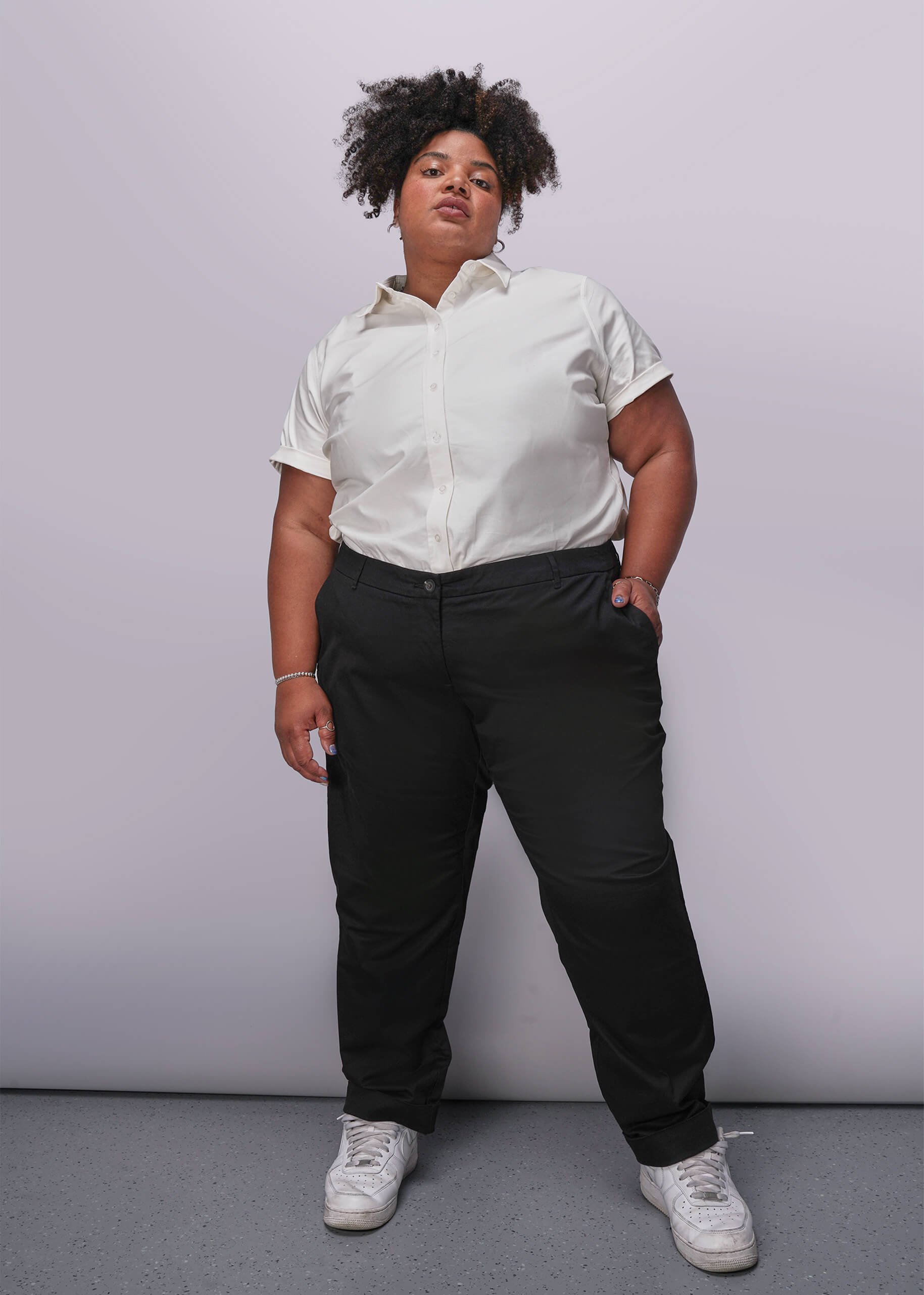 1X=Person wearing a white button up shirt and black pants against a plain background