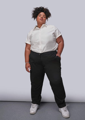 1X=Person wearing a white button up shirt and black pants against a plain background