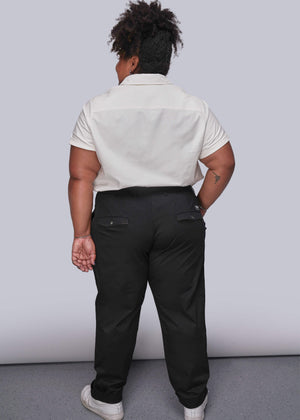 1X=Person wearing a white shirt and black pants against a plain background