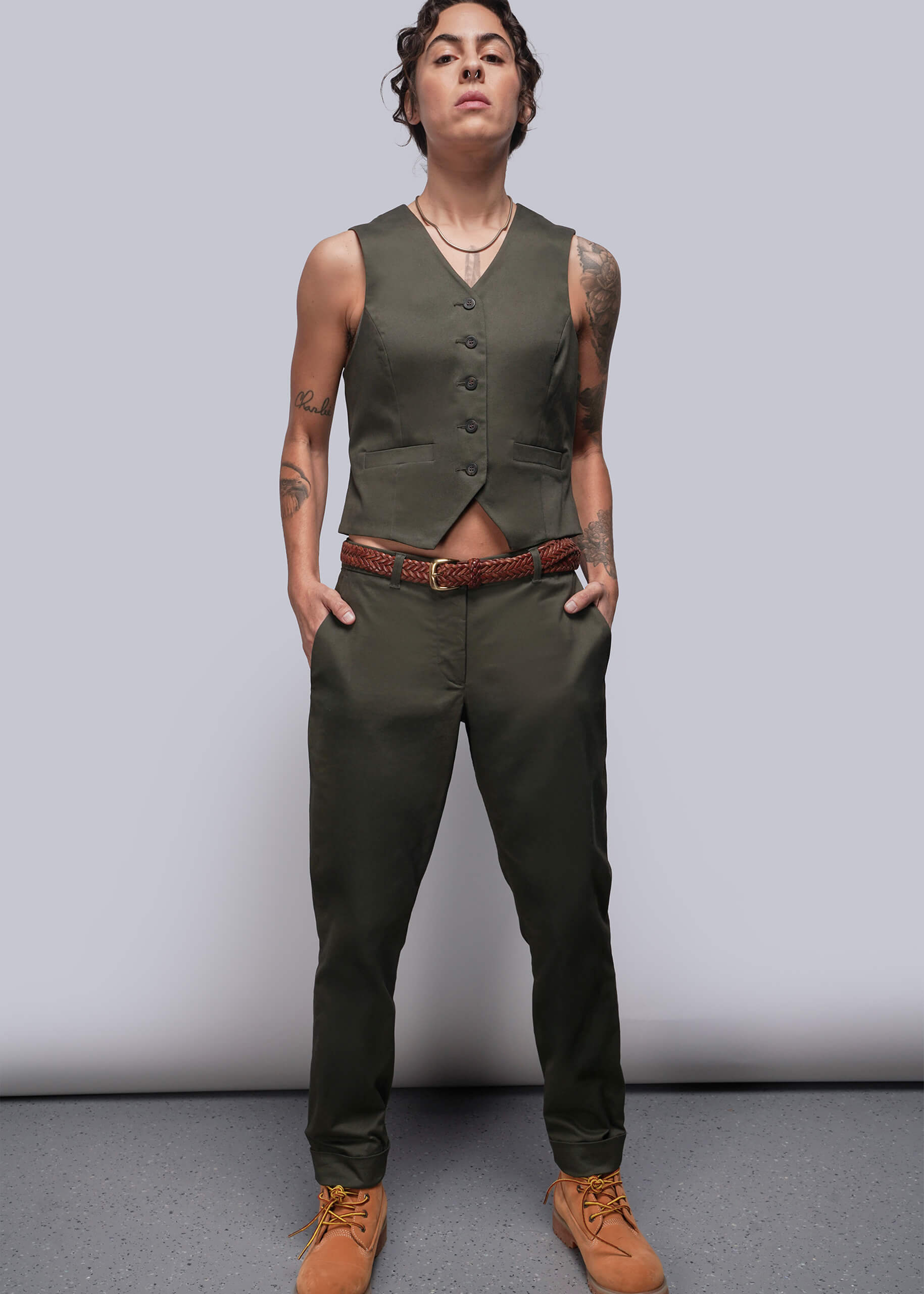 S=Person wearing a green vest and pants with a plain background