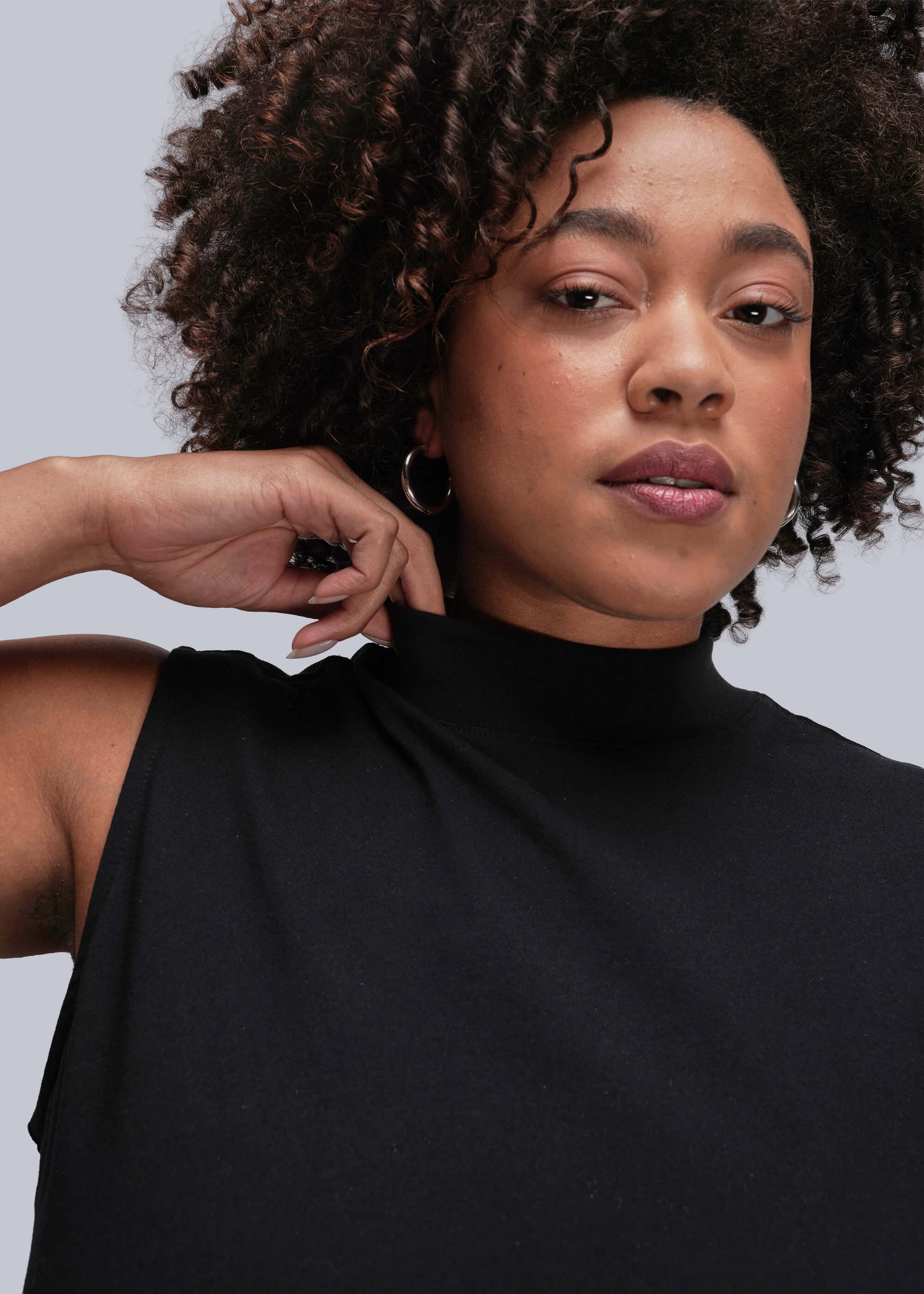 1X=Person wearing a black sleeveless top against a gray background
