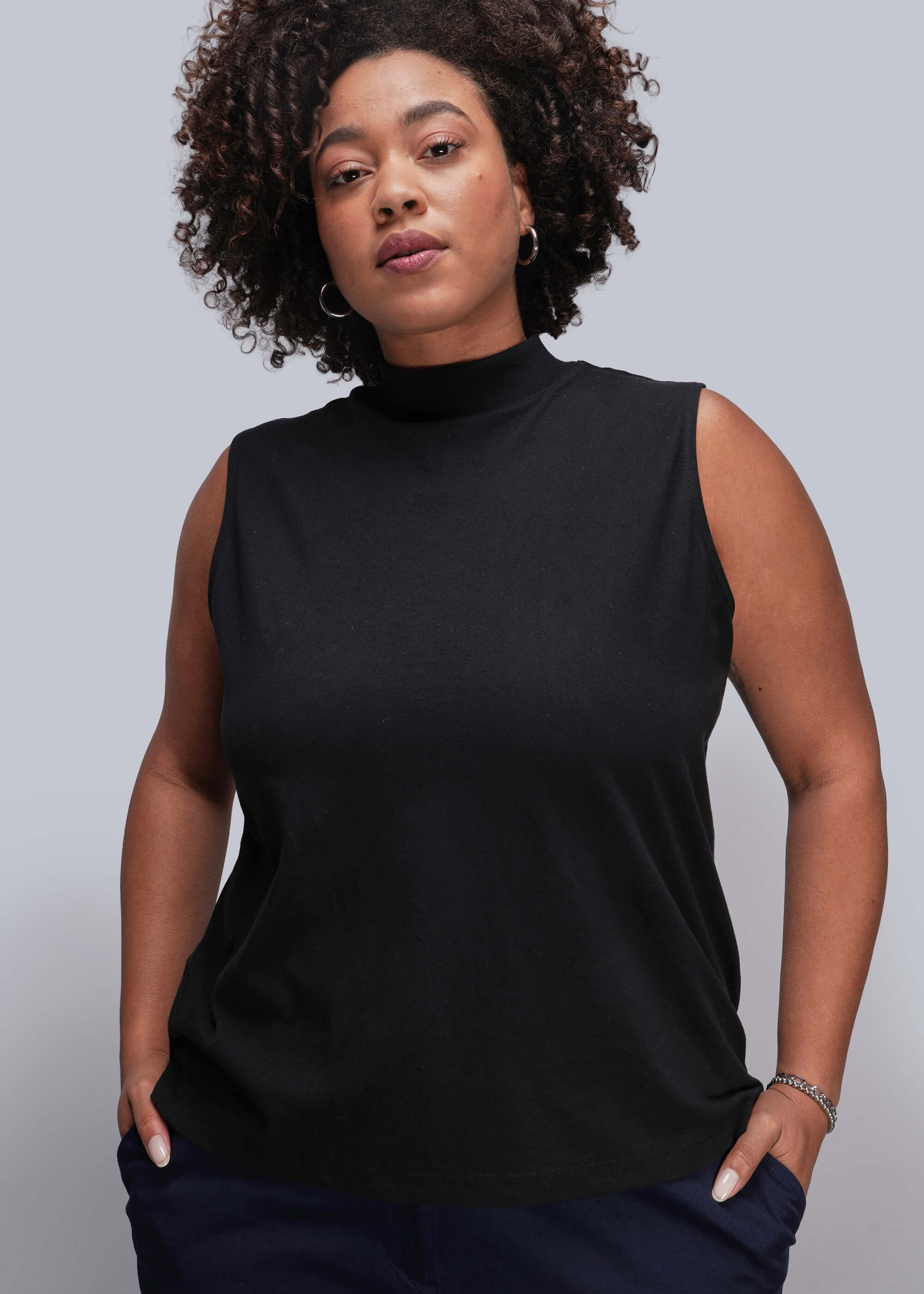1X=Person wearing a black sleeveless top against a plain background
