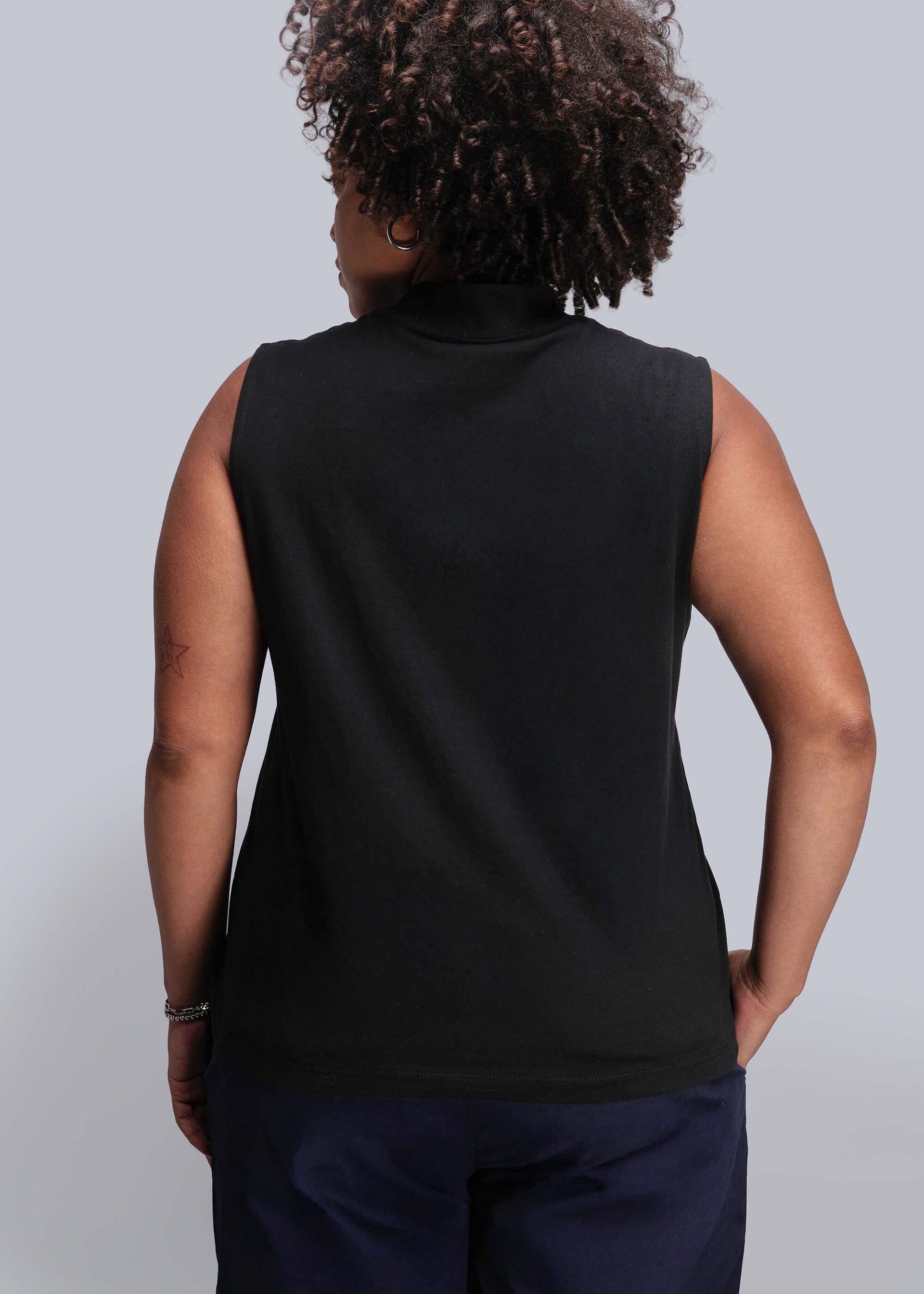 1X=Back of person wearing a black sleeveless top against a plain background