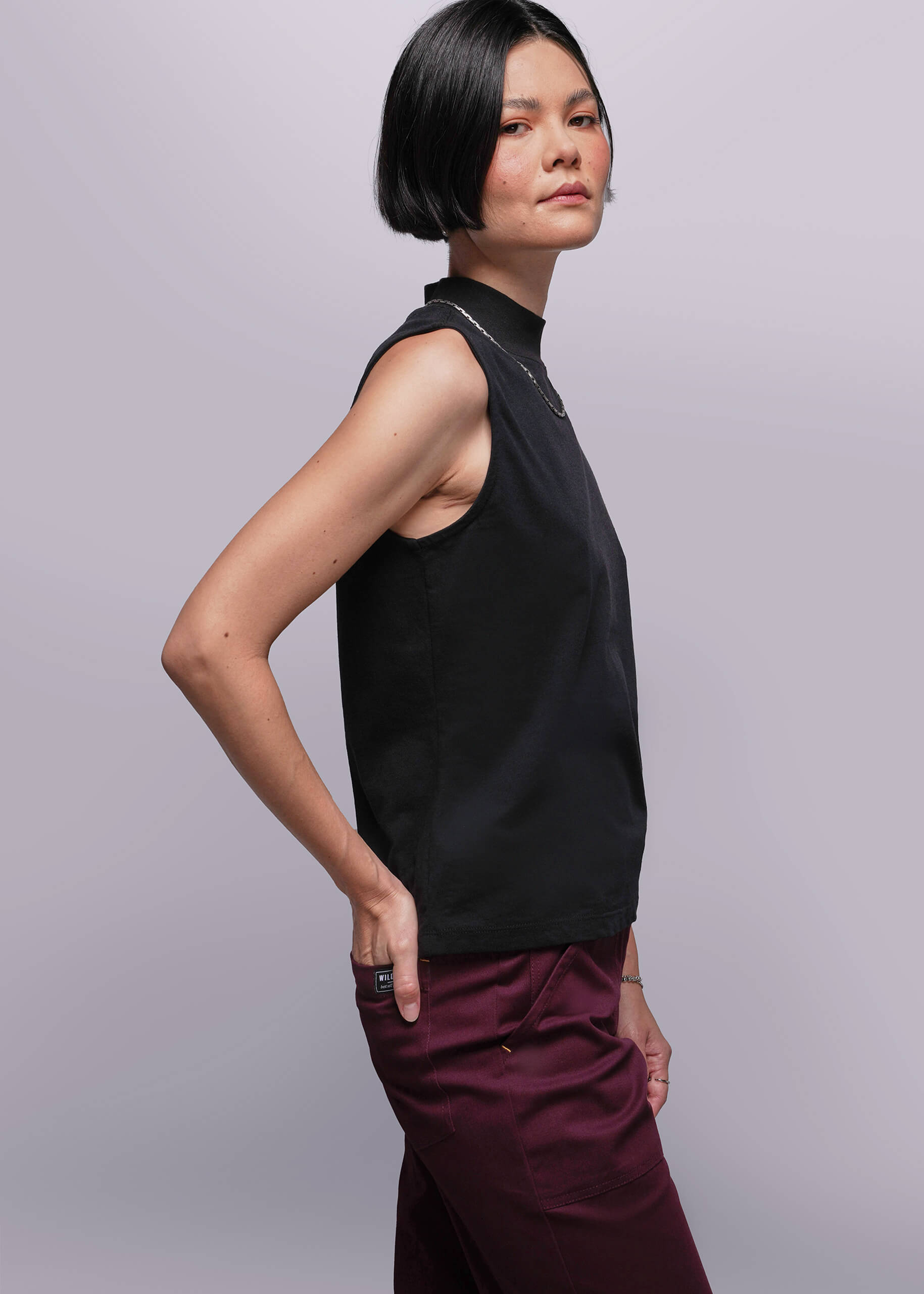 S=Person wearing a black sleeveless top and maroon pants against a light gray background