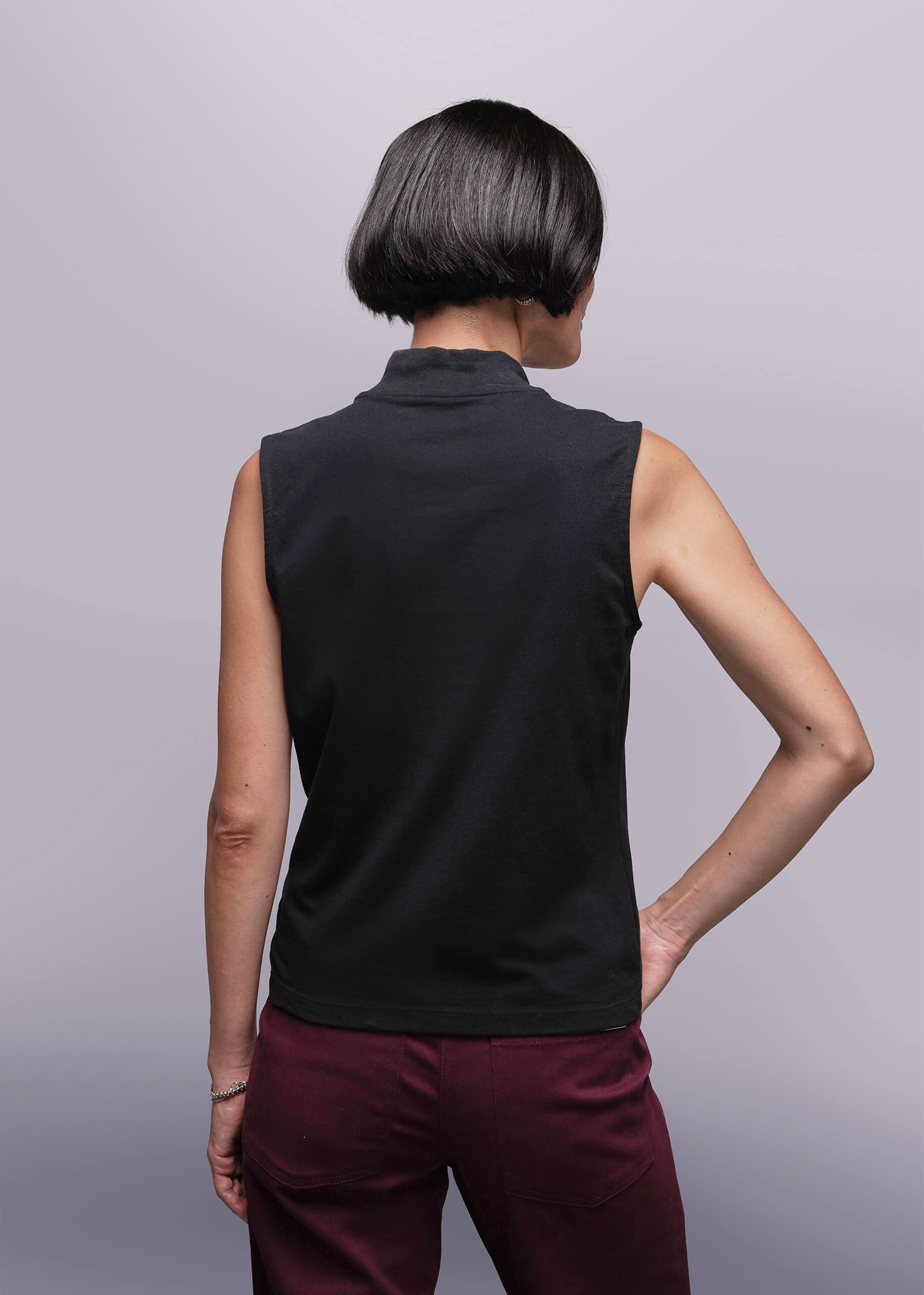 S=Person wearing a black sleeveless top and maroon pants against a light gray background