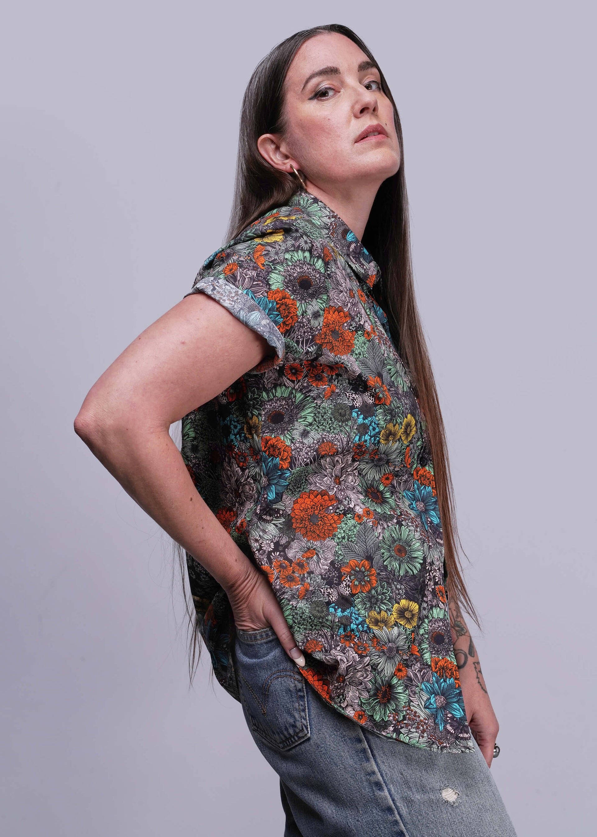 S=Woman wearing a colorful floral shirt against a gray background